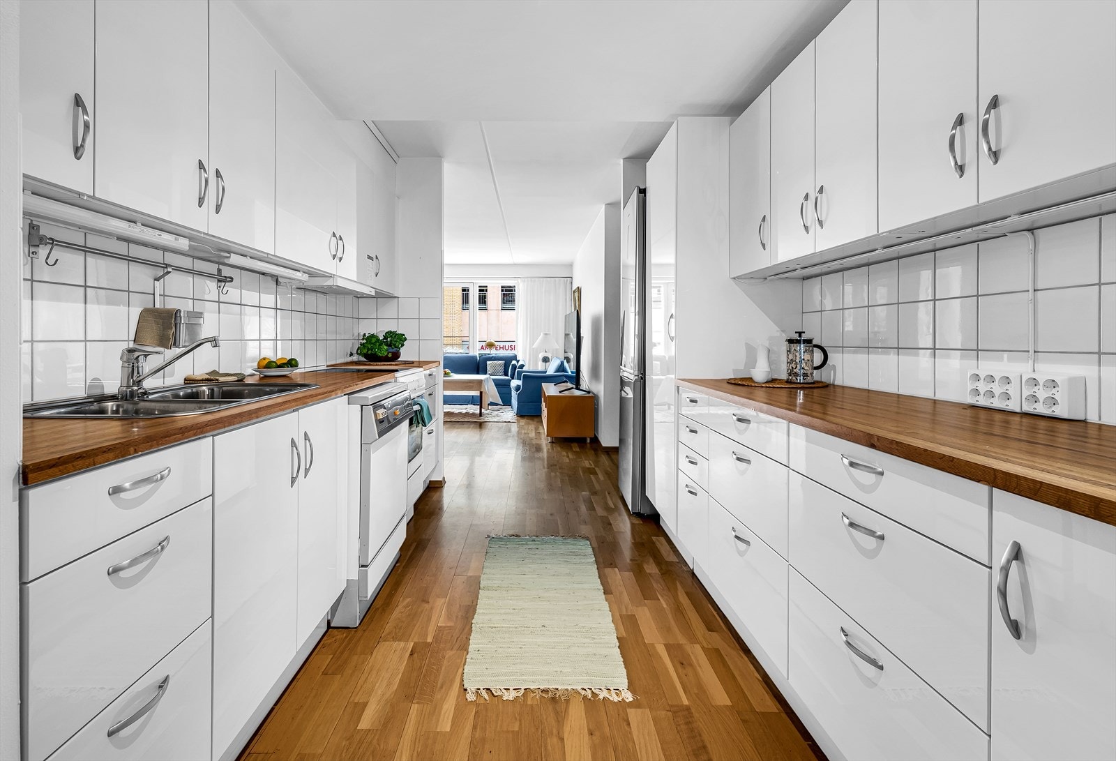 Kjøkken består av glatte hvite fronter, benkeplate i laminert spon, med nedfelt kum i stål med ett-greps blandebatteri. Integrert ventilator med avtrekk. Galleribilde