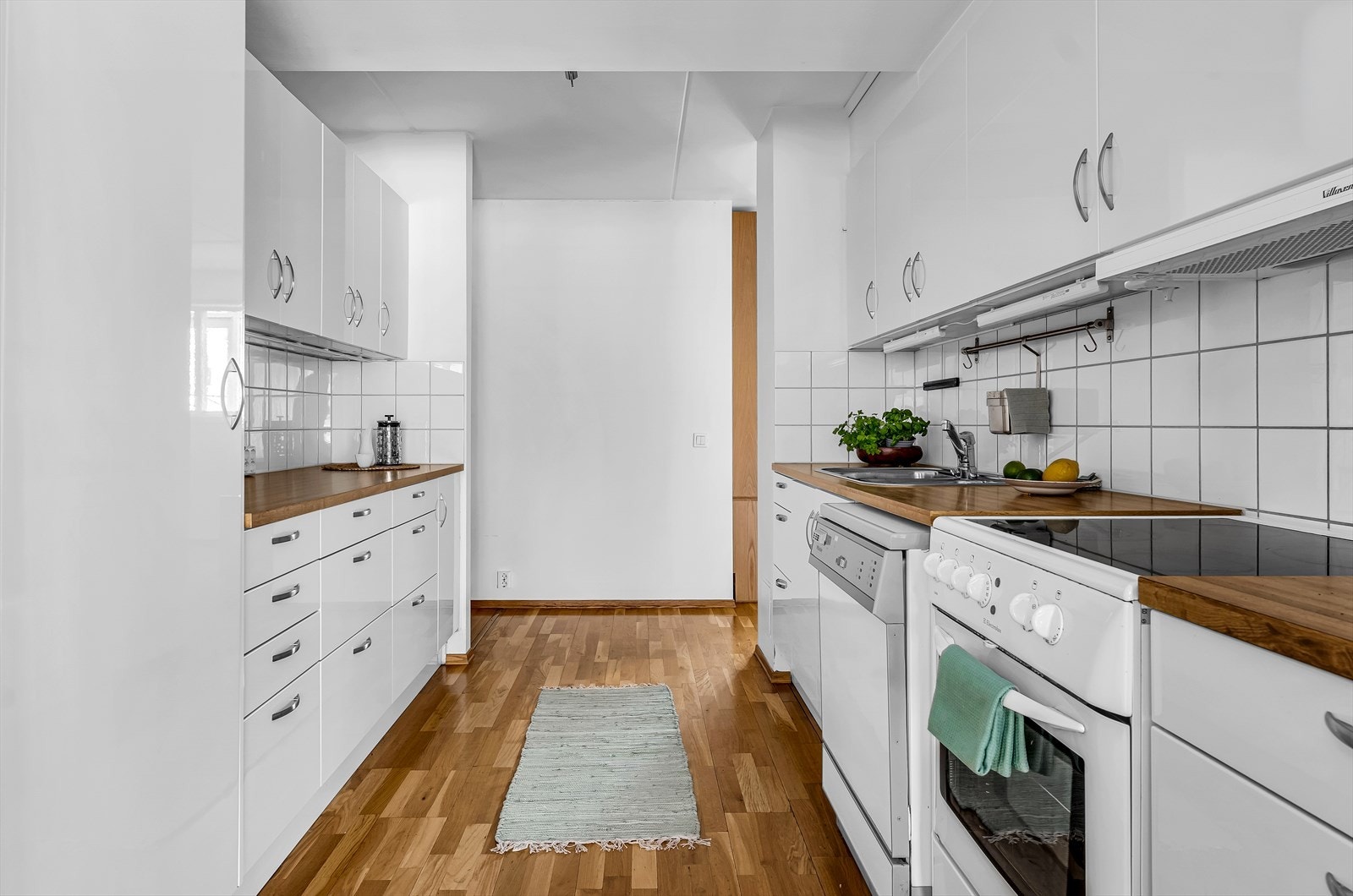 Kjøkken består av glatte hvite fronter, benkeplate i laminert spon, med nedfelt kum i stål med ett-greps blandebatteri. Integrert ventilator med avtrekk. Galleribilde