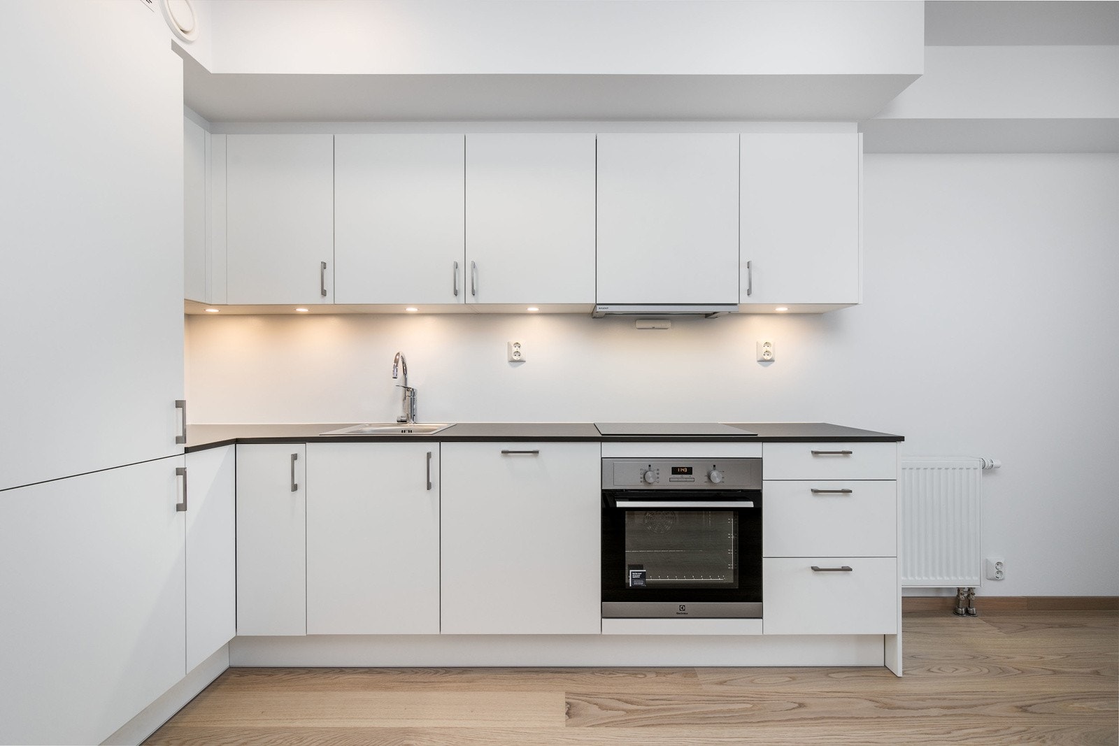 Lekkert kjøkken utformet i vinkel, med integrerte hvitevarer. Galleribilde