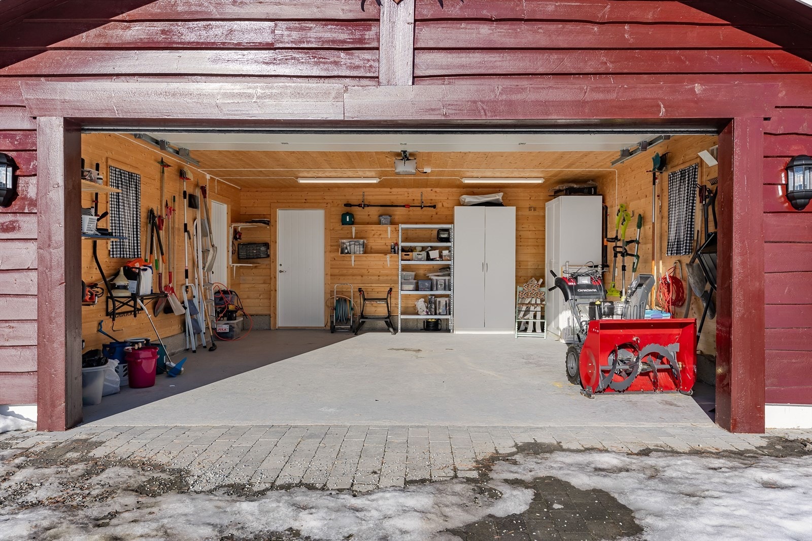 Garasjen har plass til to biler og er praktisk innredet med skap, skuffer og knagger for oppbevaring av redskap og utstyr. Galleribilde