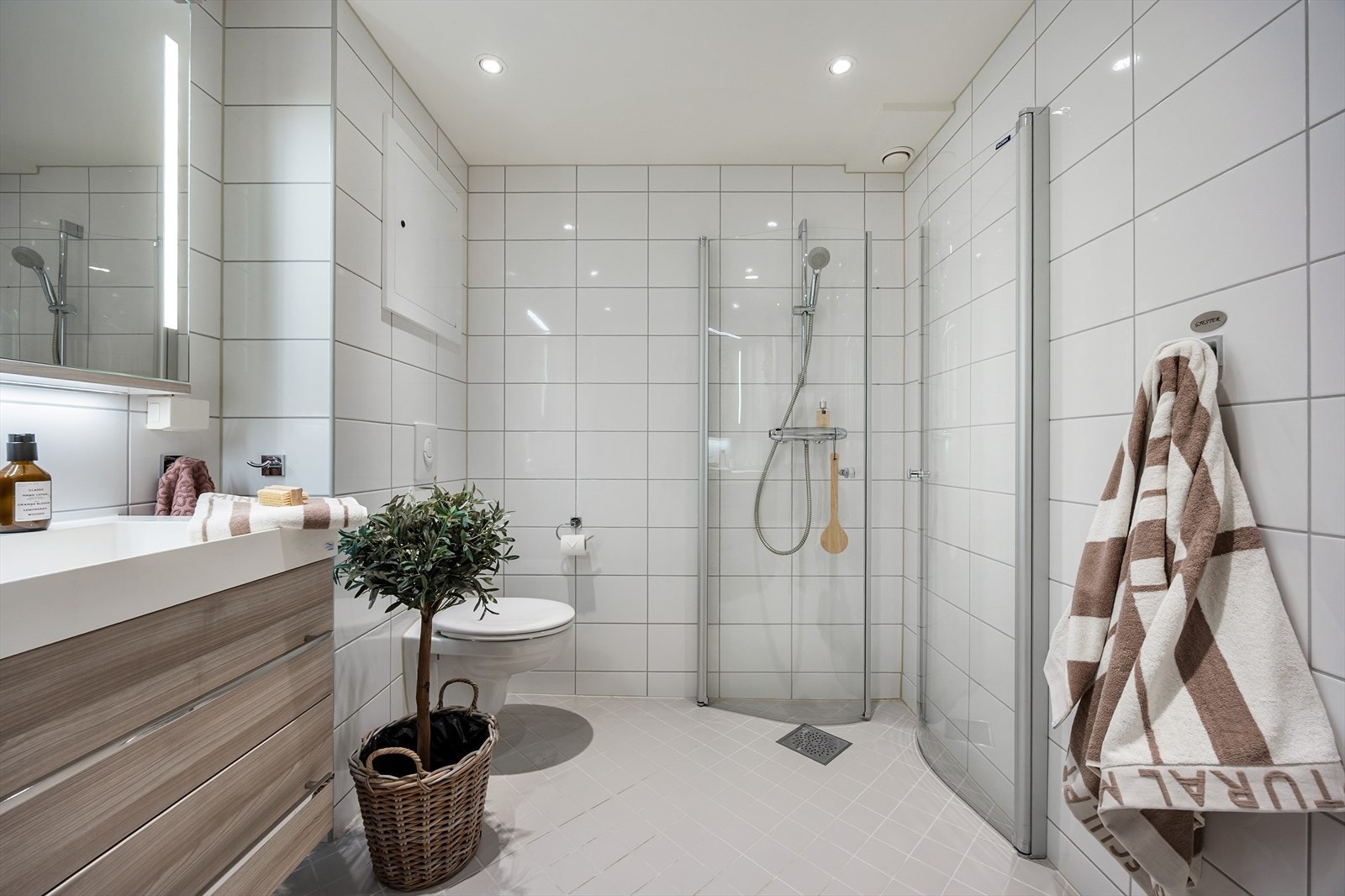 Innredningen består av vegghengt toalett, servant med skuffeinnredning, speilskap med belysning og dusj direkte på gulv. Galleribilde