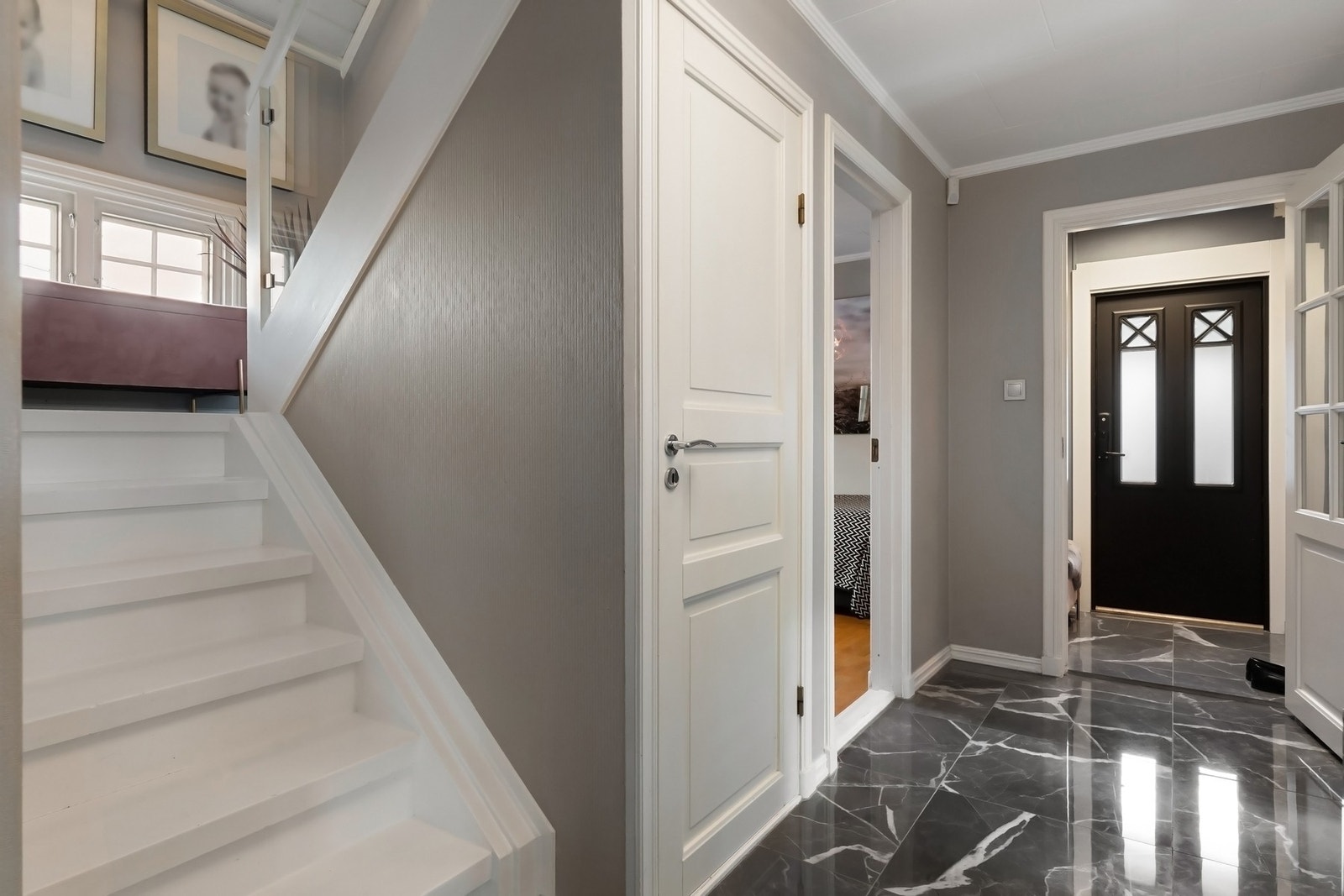 En hvitmalt trapp med glassrekkverk fører opp til andre etasje. Galleribilde