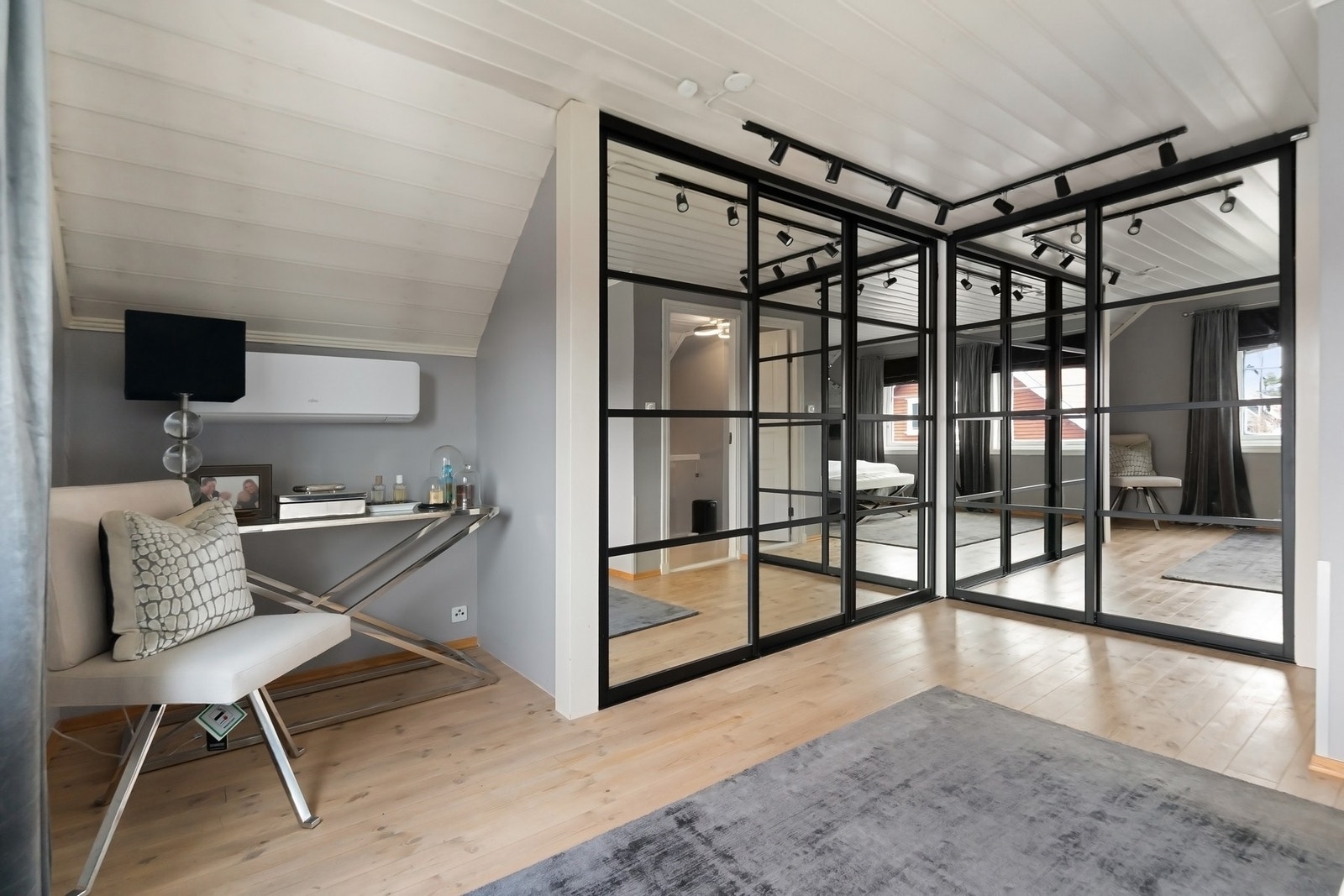 Det største rommet var tidligere to rom, en løsning som er mulig å tilbakeføre. På dette rommet er det montert varmepumpe og store skyvedørsgarderober med speilfronter og sort omramming. Galleribilde