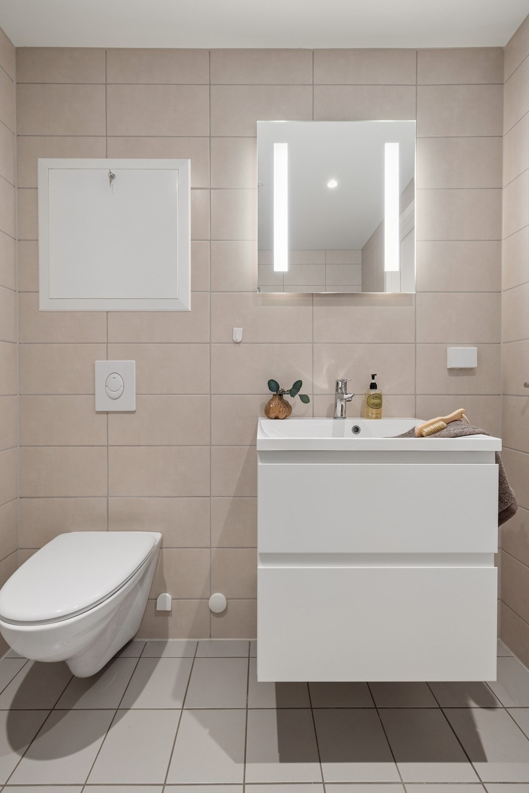 Badet er innredet med baderomsmøbel med hvite fronter, heldekkende servant og speil med integrert belysning. Galleribilde