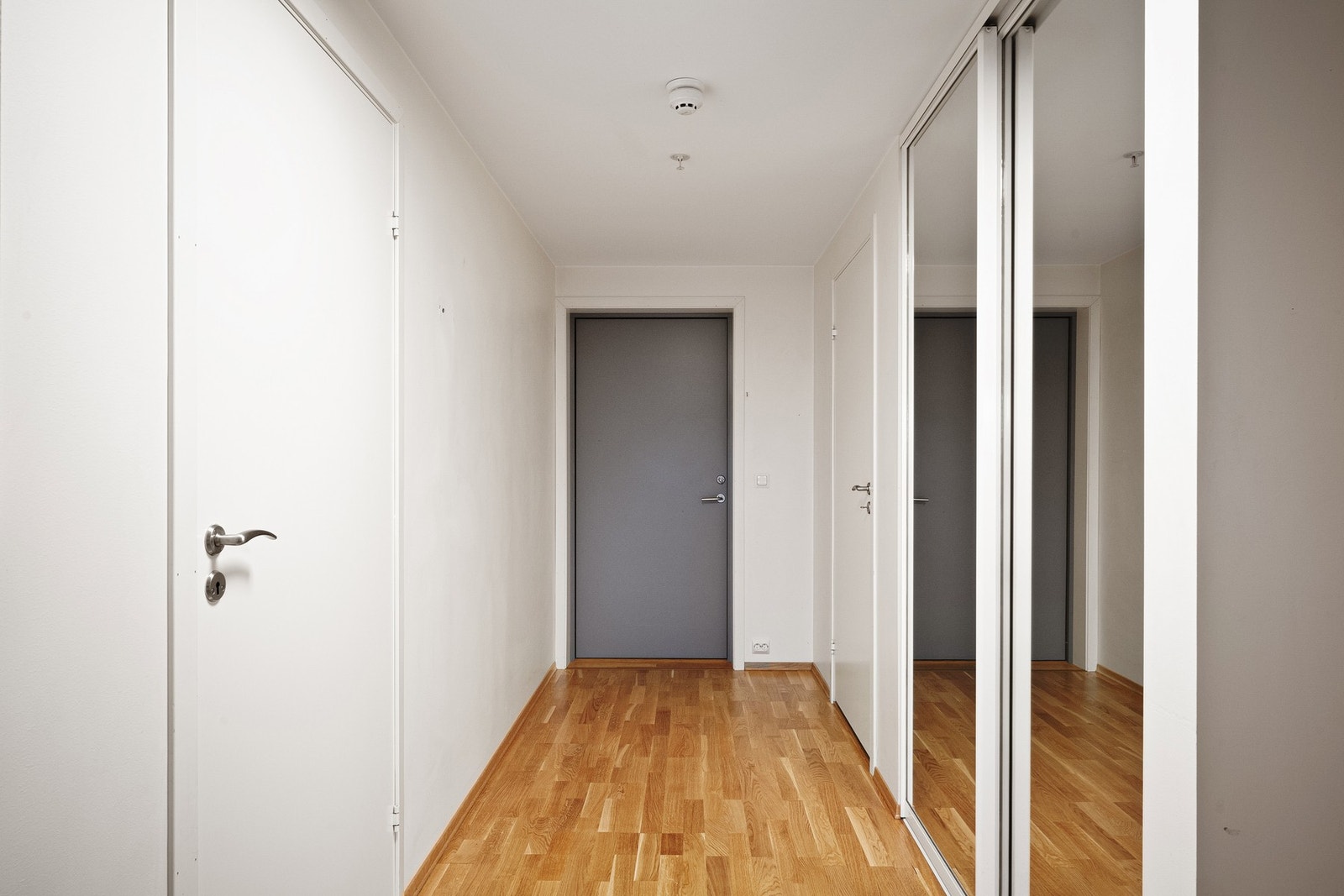 Inngangsparti med lys og romslig gang, med praktisk skyvedørsgarderobe til yttertøyet Galleribilde