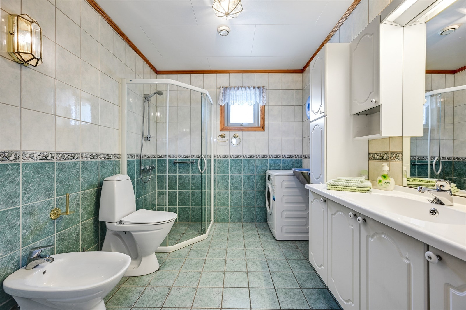 Badet er romslig med flislagte overflater og opplegg for vaskemaskin. Galleribilde