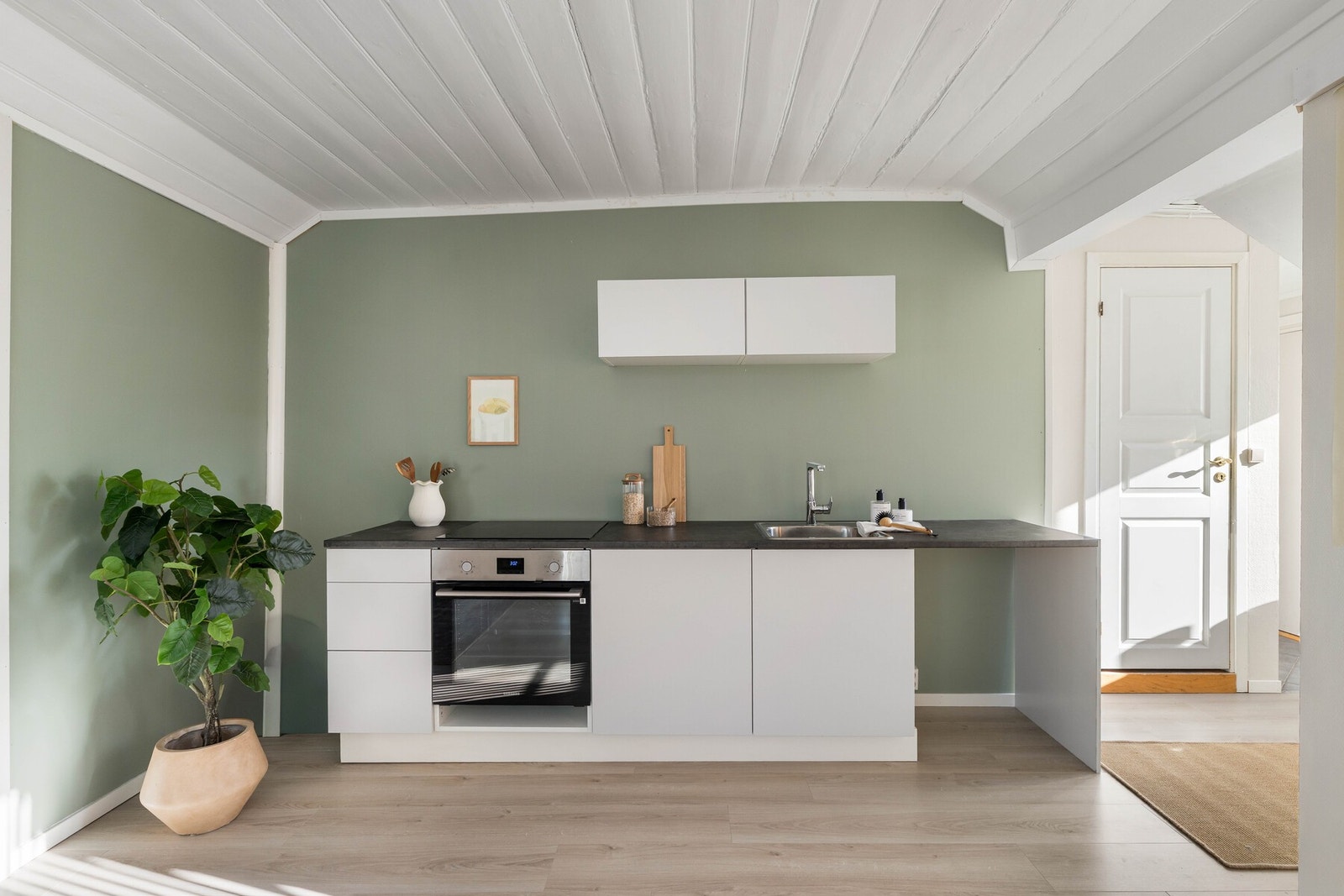 Stilren kjøkkeninnredning fra 2025 med slette fronter og laminat benkeplate med nedfelt oppvaskkum i rustfritt stål. Galleribilde