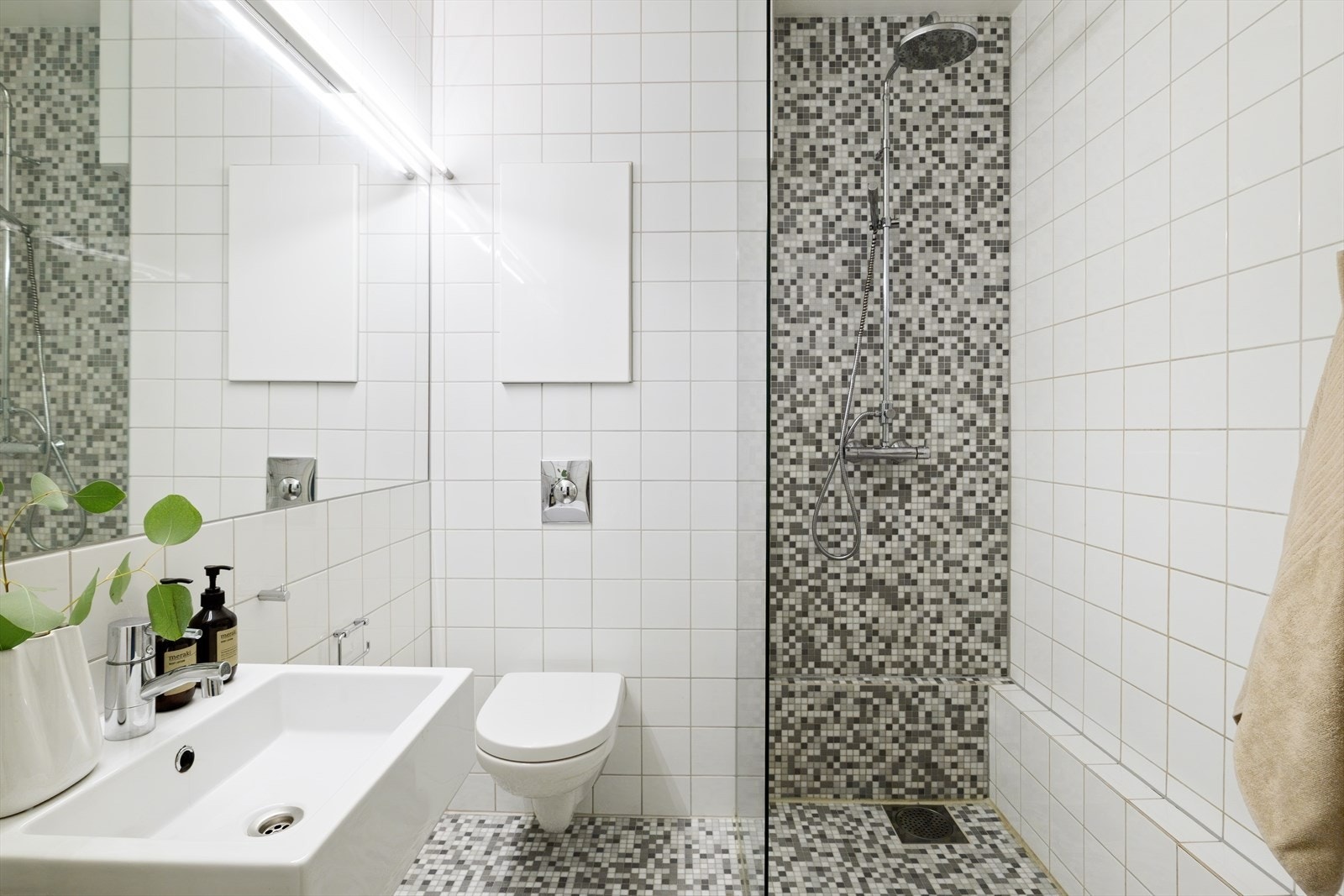 Innredningen består av servant med nedfelt kum og speil med belysning. Dusjen er plassert i hjørnet og har håndholdt dusjarmatur og dusjvegger. Det er montert vegghengt toalett. Galleribilde