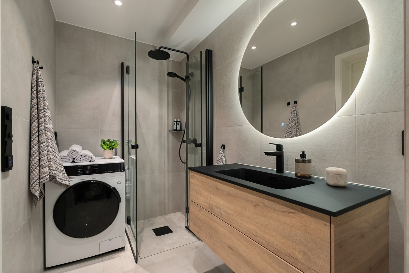 Badet er utstyrt med gulvvarme, veggmontert toalett, servantinnredning og vegghent speil med integrert belysning. Innfellbare og plassbesparende dusjdører Galleribilde