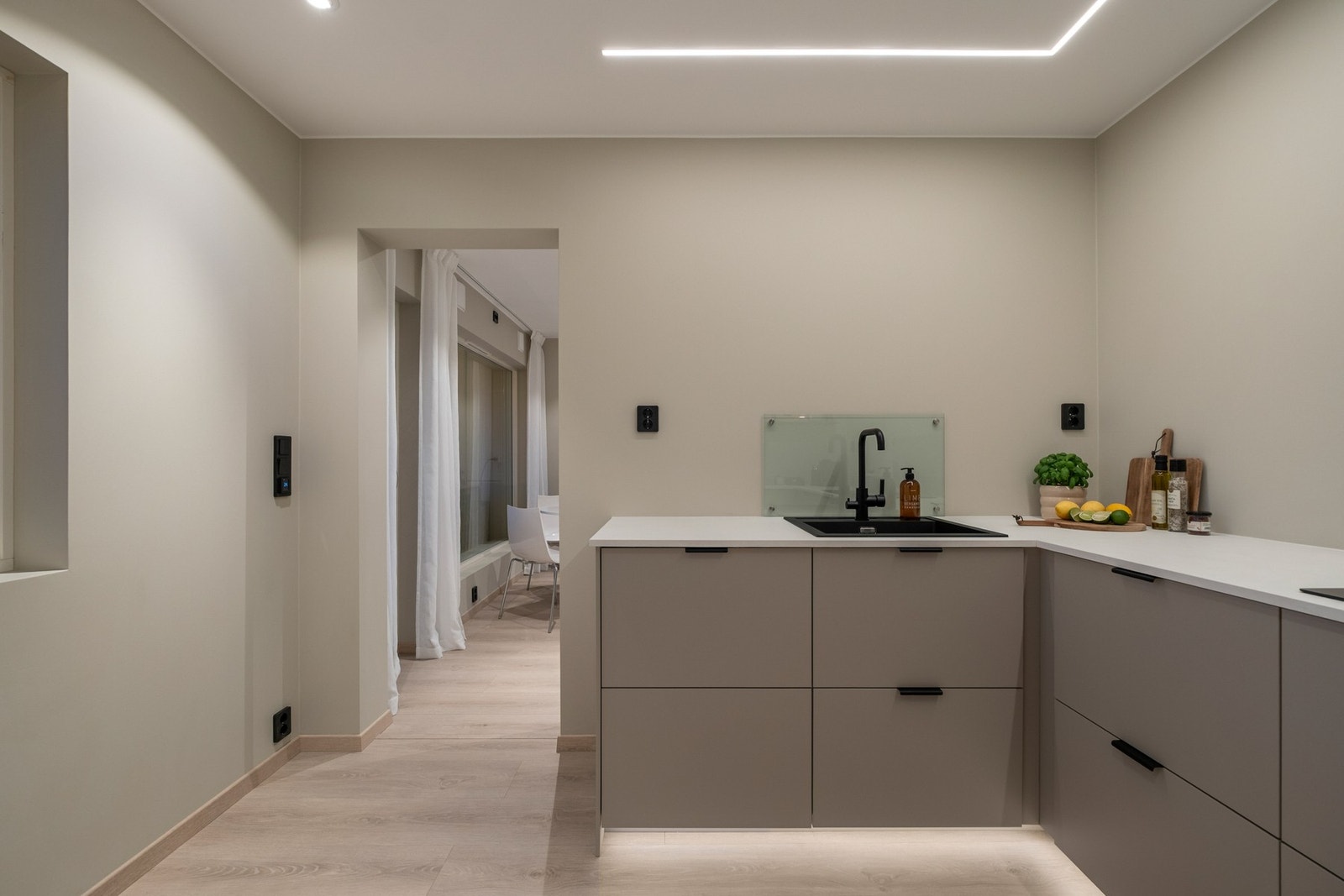 Legg merke til de gjennomgående sorte detaljene i form av håndtak, vask, kjøkkenarmatur, stikkontakter og brytere Galleribilde