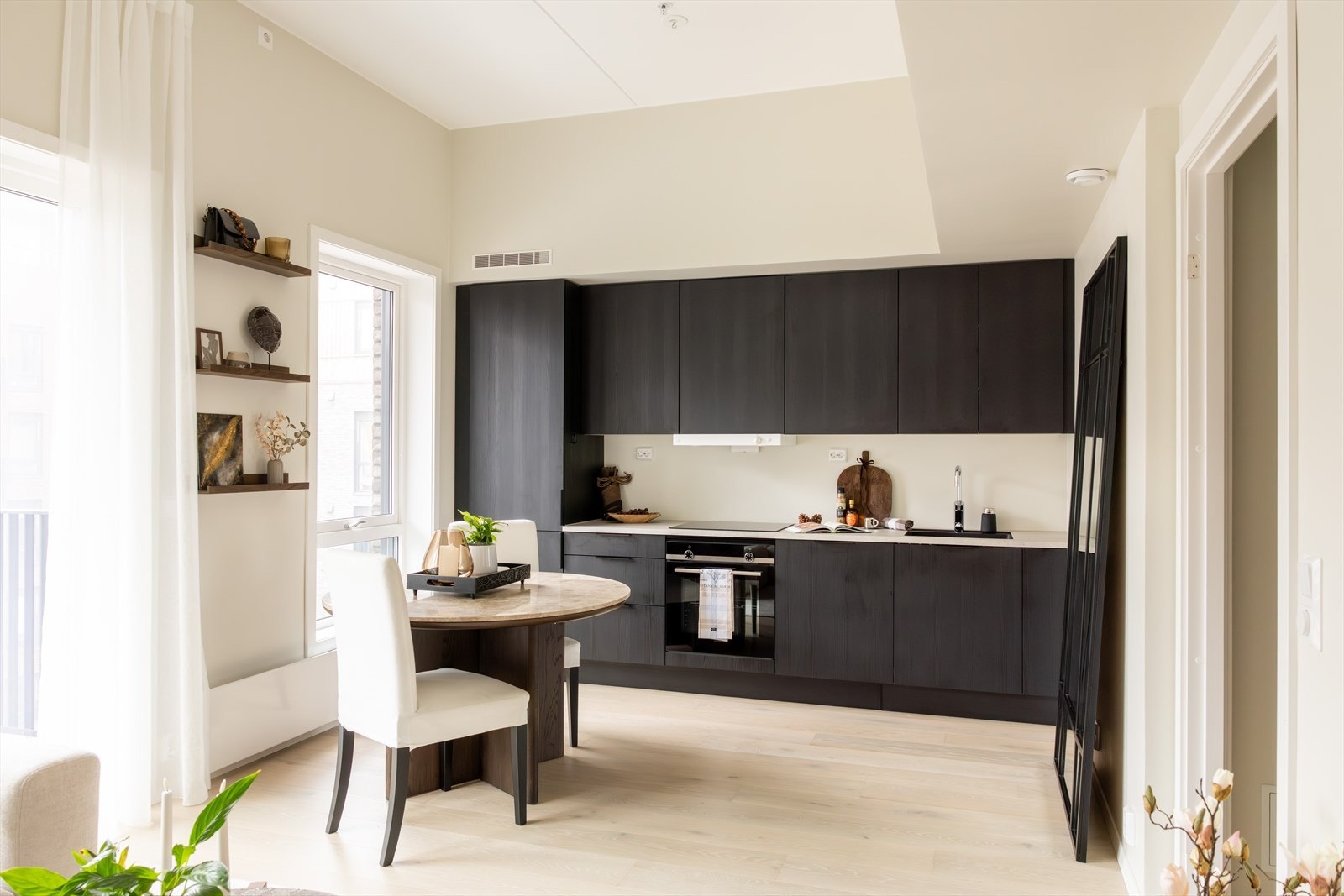 Stilrent HTH-kjøkken med god skap- og benkeplass, i åpen løsning mot stuen. De rene linjene og den mørke kjøkkeninnredningen skaper en fin kontrast til de lyse veggene og gulvet, og gir kjøkkenet et moderne uttrykk. Galleribilde