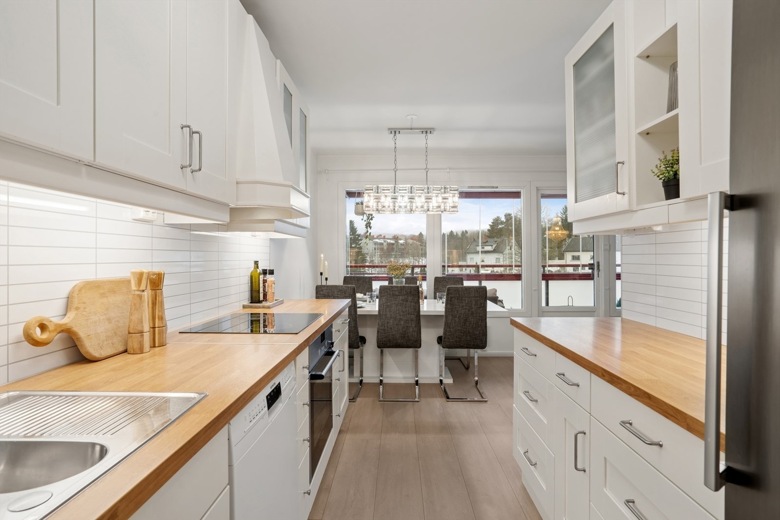 Lyst og tidsriktig kjøkken fra 2016 med profilerte fronter, hvor enkelte overskap har glassdører, og benkeplate i laminat. Galleribilde