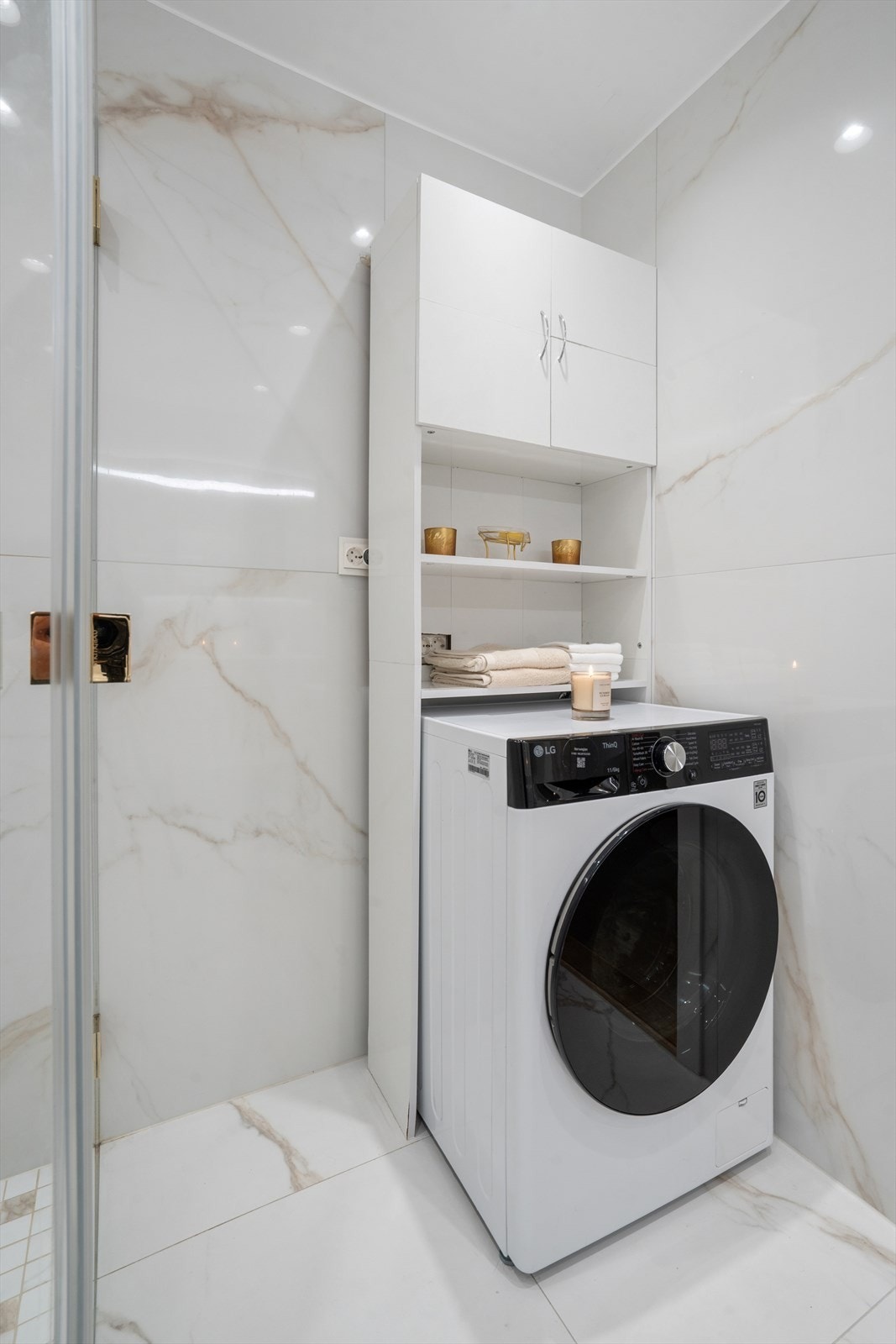 Badet er innredet med servant, speil med integrert lys, vegghengt toalett, svingbare dusjvegger i glass og opplegg for vaskemaskin. Galleribilde