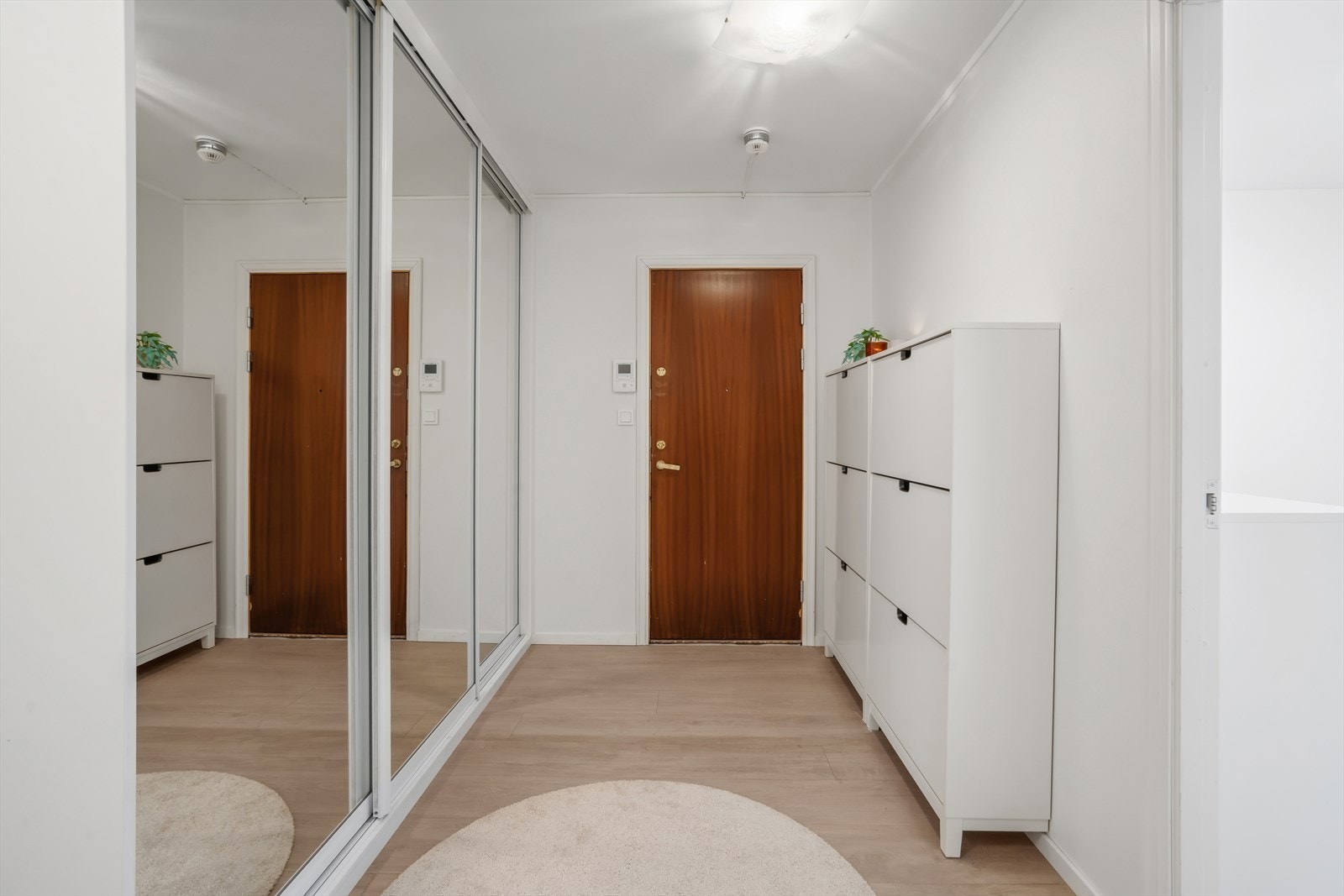 Lys og oversiktlig entré med skyvedørskap og moderne digitalt callinganlegg. Galleribilde