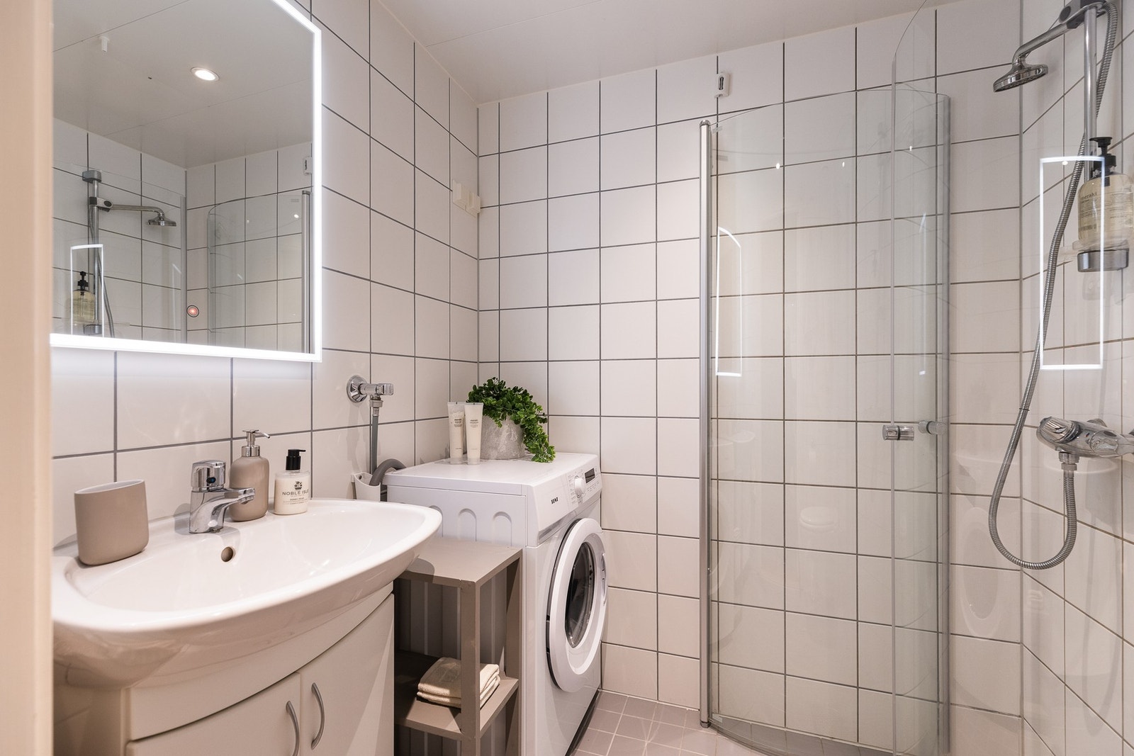 Innbydende og tidløst flislagt baderom med termostatstyrte varmekabler i gulv og downlights i himling. Uttak til vaskemaskin. Galleribilde