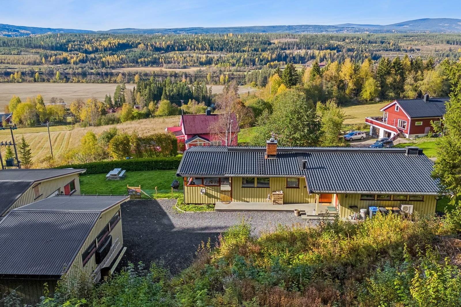 En enebolig med overbygget terrasse og stor hage - omgitt av frodige, grønne omgivelser. Galleribilde