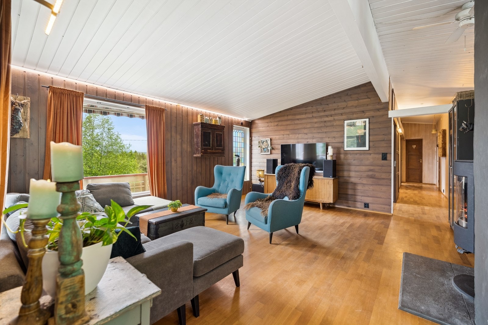 Stuen har store vindusflater mot terrassen og panel i varme toner for ekstra sjarm. Galleribilde