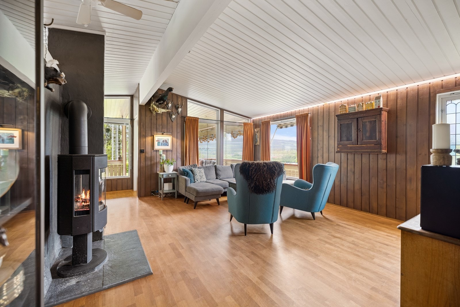 Romslig stue med åpen løsning mot spisestue og stemningsfull vedovn fra 2023. Galleribilde