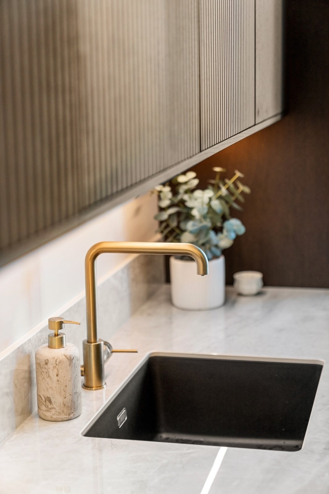 Påkostet benkeplate i keramikk, kombinert med underlimt vaskekum og armatur i messing, gir kjøkkenet et eksklusivt preg. Galleribilde