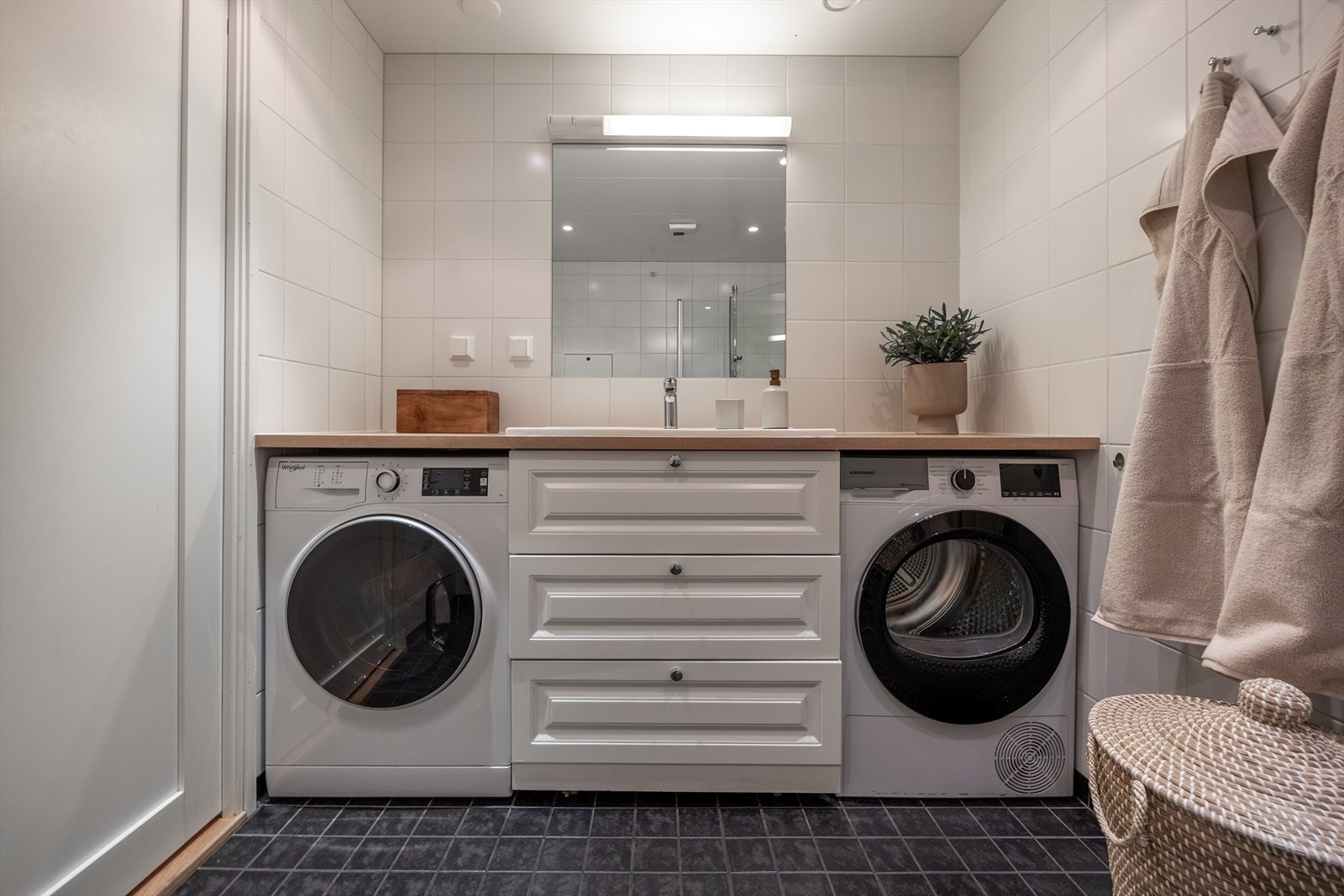 Praktisk og pen baderomsinnredning og benkeplate fra 2023 med opplegg til både vaskemaskin og tørketrommel. Galleribilde