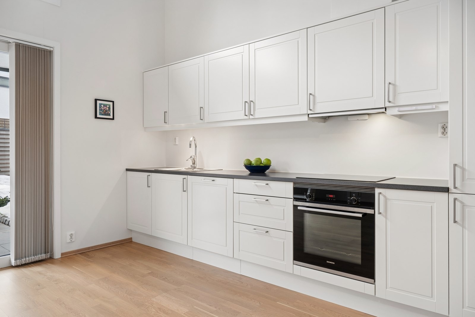 Kjøkkenet er innredet med profilerte fronter, laminert benkeplate, integrerte hvitevarer og både vannstopper og komfyrvakt. Galleribilde