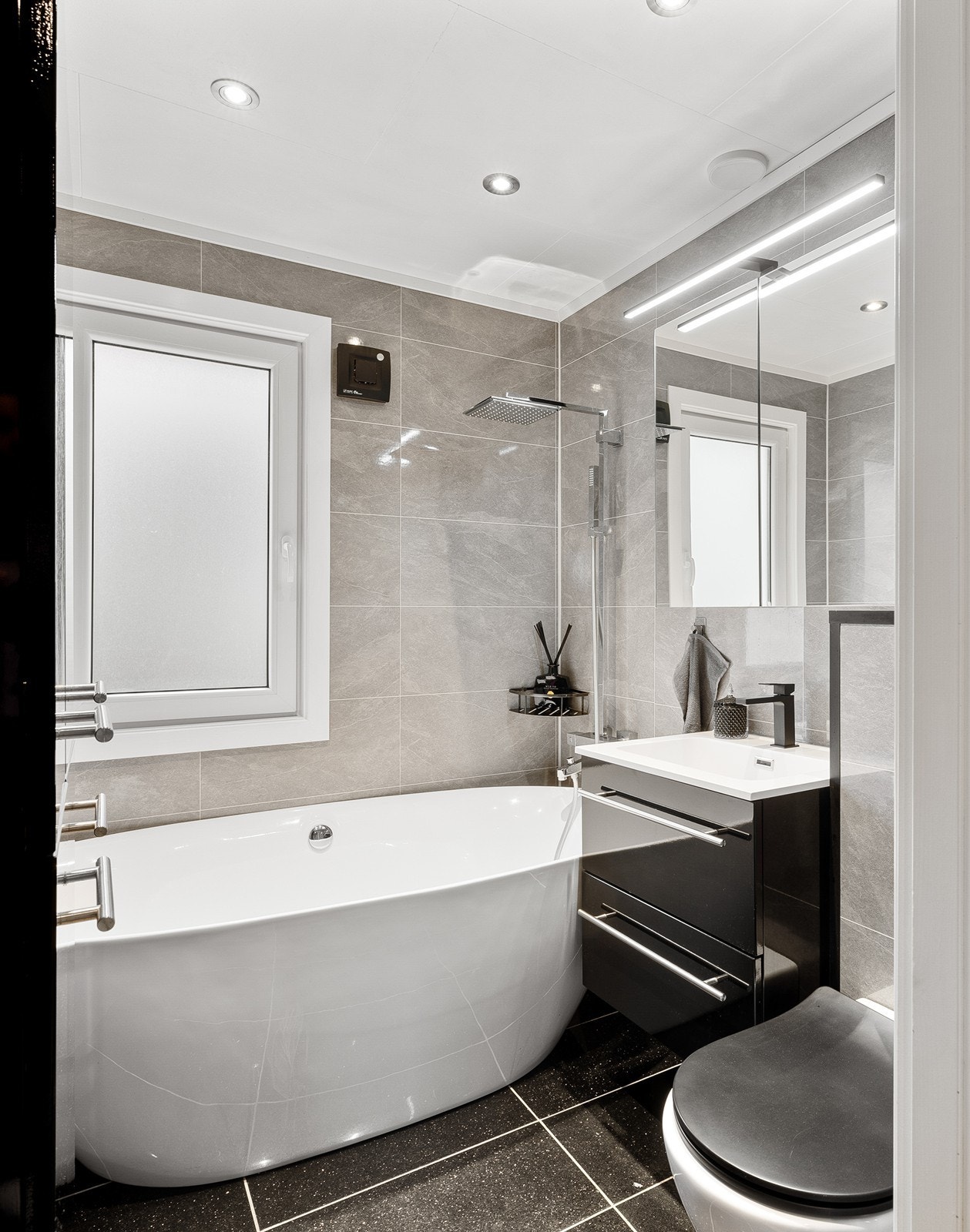 Etasjen har et bad med fliser på gulv og baderomsplater på vegger. Innredningen består av et underskap/overskap, servant, speil, lys, stikk og et badekar med dusjing direkte på vegg. Galleribilde