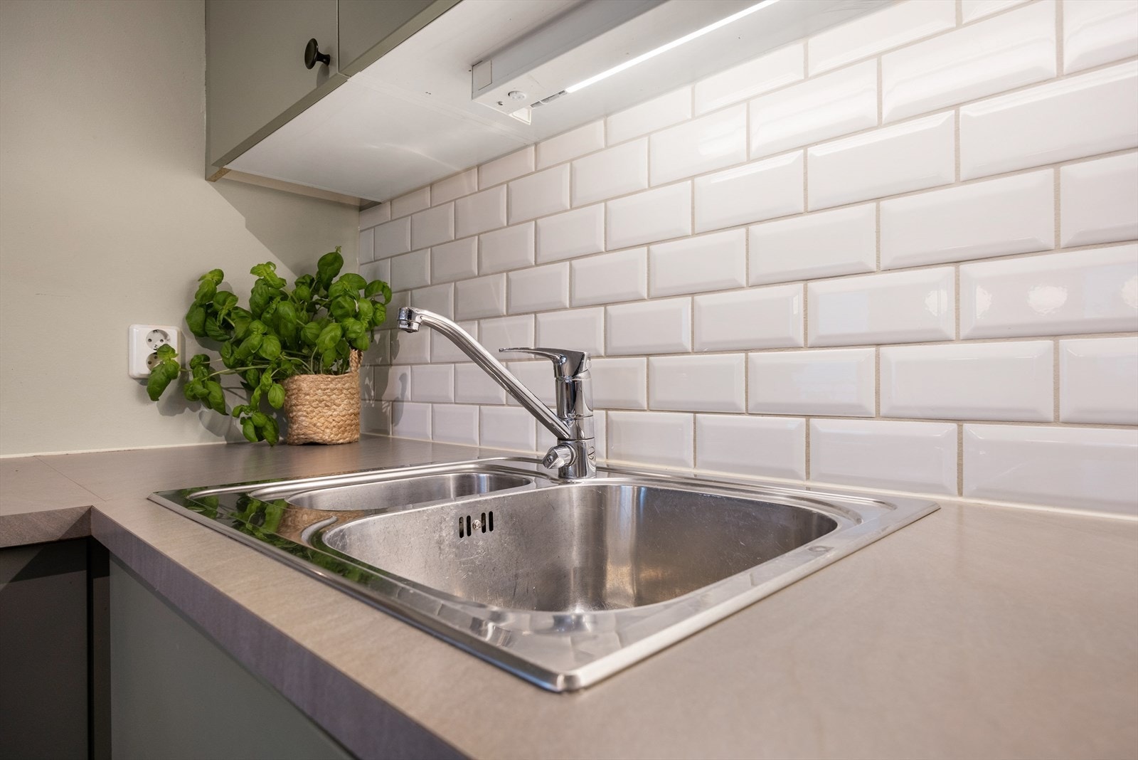 Laminatbenkeplate med nedfelt oppvaskkum og fliser på veggen over. Galleribilde