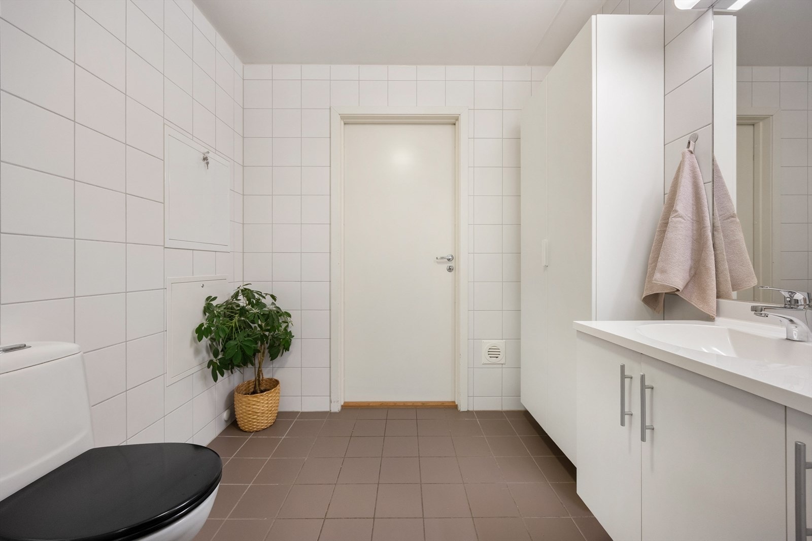 Badet er utstyrt med vegghengt toalett og en servantseksjon med skuffer for oppbevaring. Galleribilde