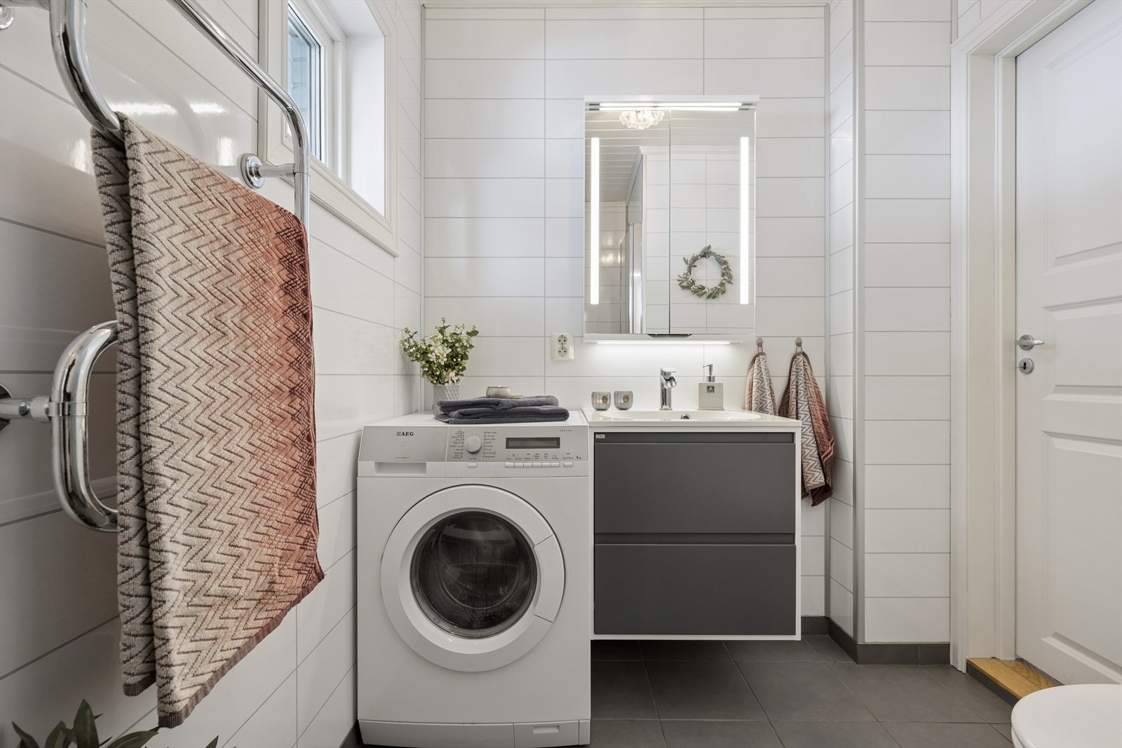 Rommet er kombinert bad og vaskerom, med opplegg for vaskemaskin og servantinnredning. Galleribilde