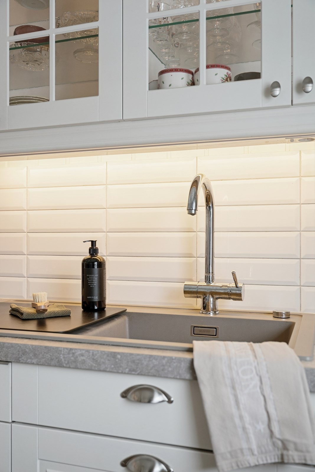 Detalj fra kjøkkenet med laminat benkeplate, kompositt kum og flislagt bakvegg. Galleribilde