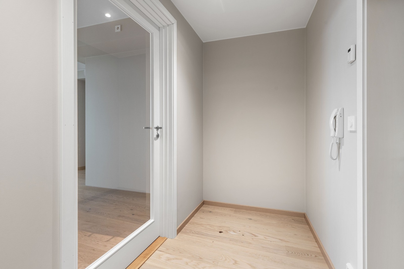 Inne blir vi ønsket velkommen i en pen entre med lysemalte vegger og 1-stavs eikeparkett på gulv. Bilde fra identisk leilighet i 1. etg. Galleribilde