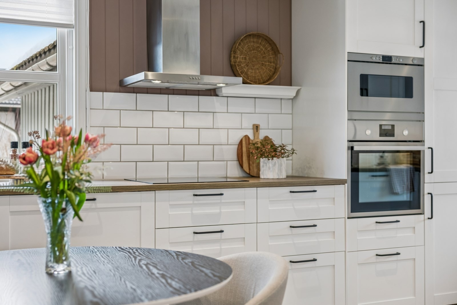 Detaljbilde fra kjøkkenet med fliser over benk og integrerte løsninger. Galleribilde