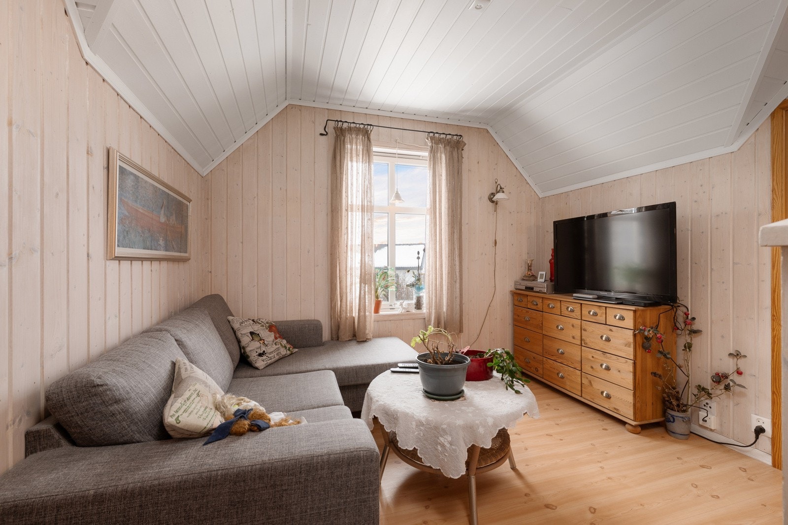 Rommet har laminat på gulvet og panel på vegger og i tak, som gir en lun atmosfære. En hyggelig loftstue med plass til sofa og tv-seksjon, perfekt som en ekstra TV-stue eller lekeområde for barna. Galleribilde