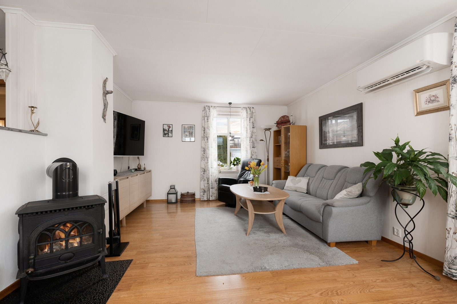 En klassisk vedovn gir supplerende varme og en hyggelig atmosfære på kalde dager. Her er det også varmepumpe fra 2019. Galleribilde