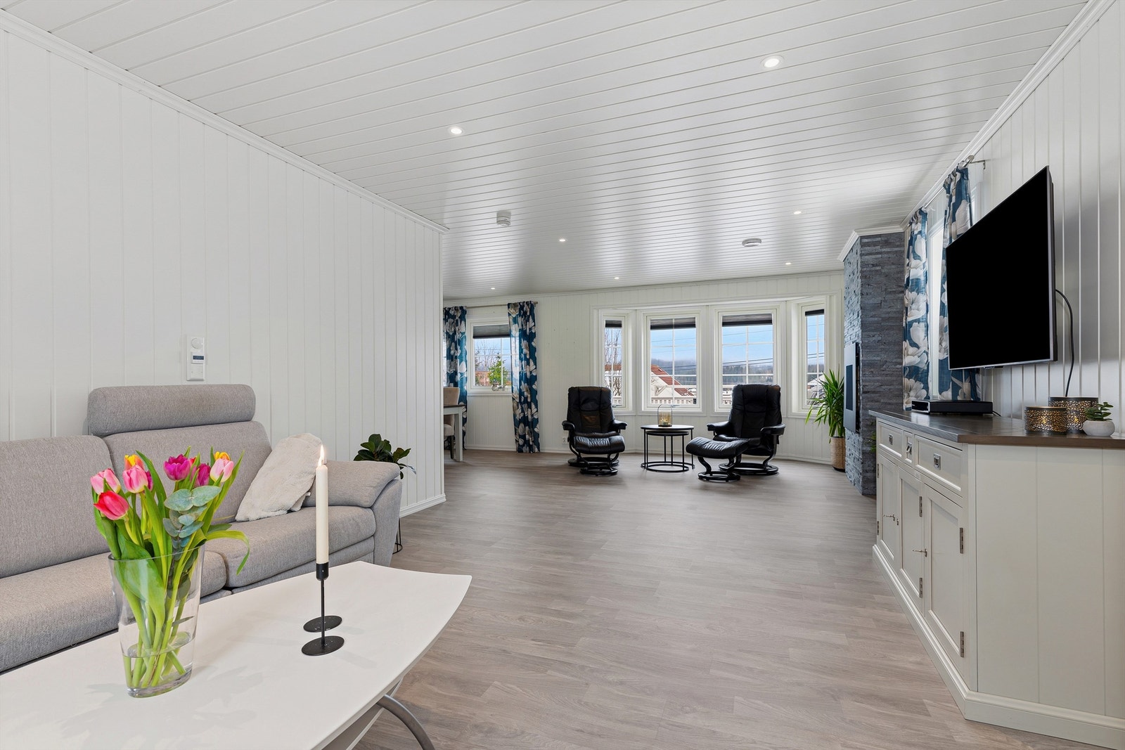 Fra stuekroken mot plass for sittegruppe ved den dekorative og stilige gasspeisen som gir lun varme på kalde dager Galleribilde