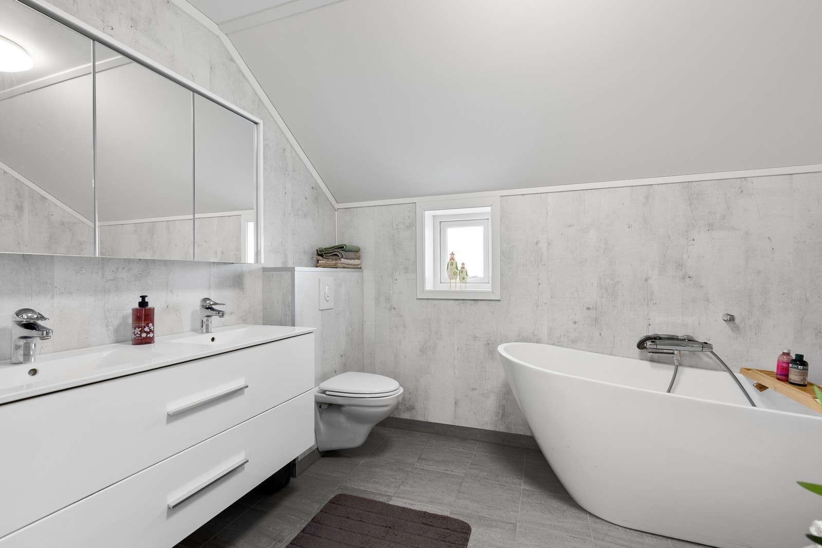 Badet i loftsetasjen har dusjkabinett, badekar, wc og servantinnredning. Det er fliser på gulv og plater på vegg. Gulv har også varmekabler. Galleribilde