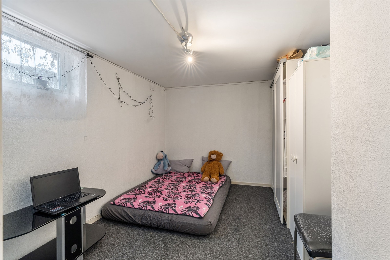 Et annet innredet rom med teppe på gulvet og plass til seng og oppbevaring. Rommet er godkjent som evt. klesbod uten vindu. Galleribilde