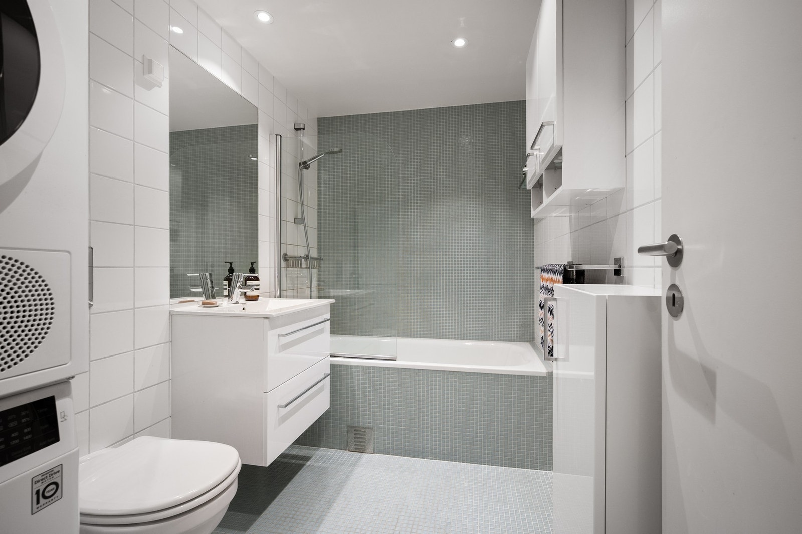 Badet har delikat innredning med flislagte vegger og gulv. Videre er det vegghengt toalett, servantskap med to skuffefronter som sikrer rikelig med oppbevaringsmuligheter. Galleribilde