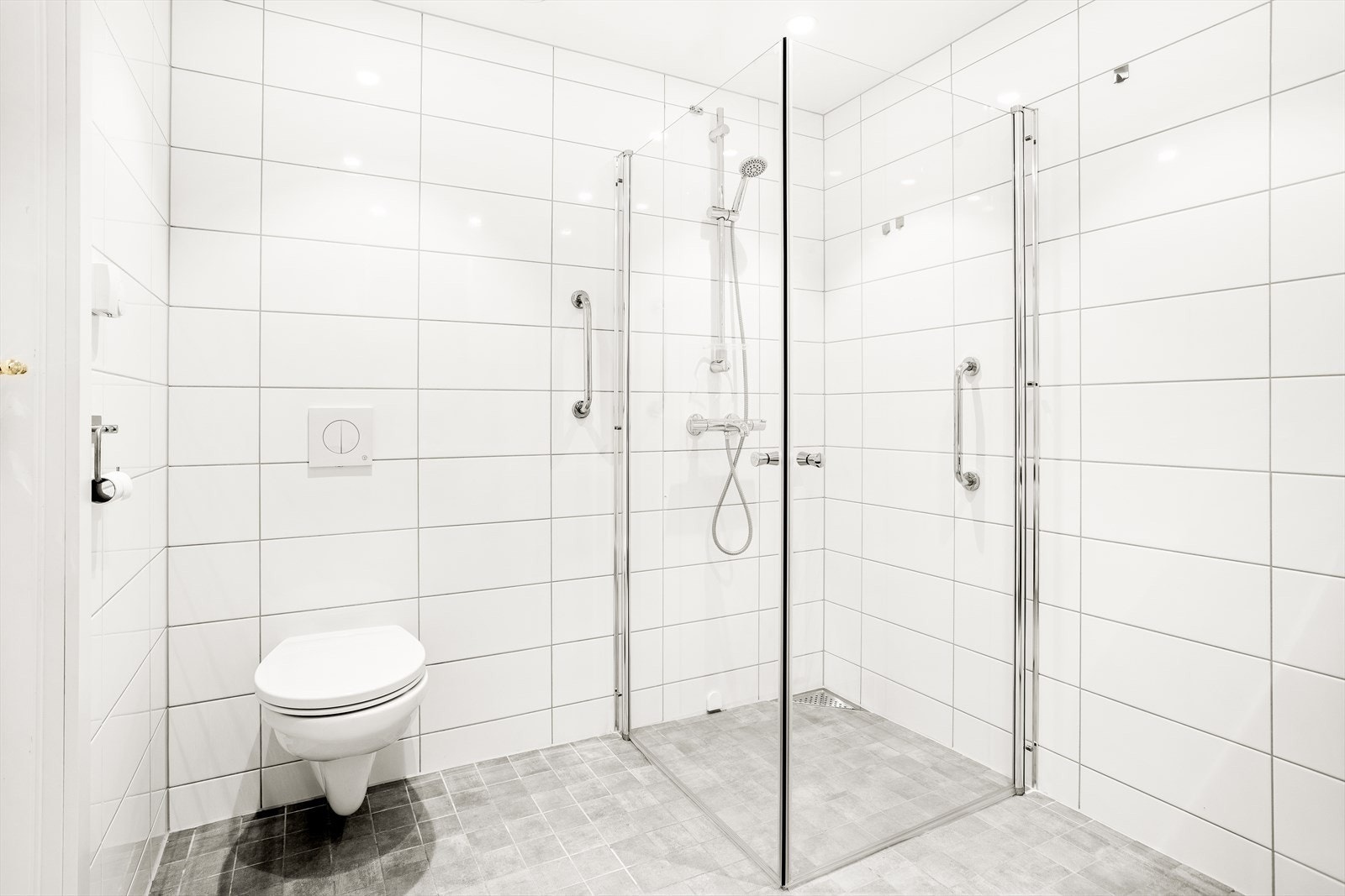 Baderommet er innredet med veggmontert klosett, nedsenket vask med innredning og speil, nedsenket dusjnisje med glassdører og opplegg til vaskemaskin/tørk. Galleribilde