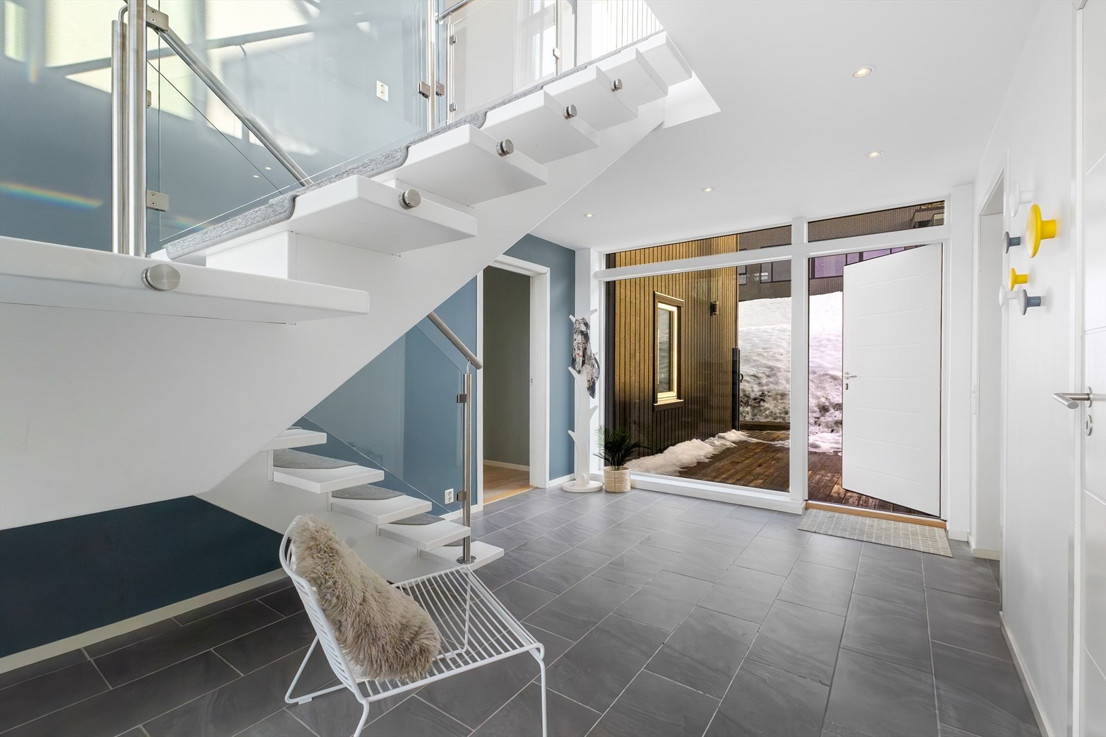Åpen entre med "svevende trapp" og ett innsig av lys av det sjeldne. Selvsagt flislagt gulv med gulvvarme. Herfra er det også utgang til en terrasse på Nord-øst siden. Galleribilde