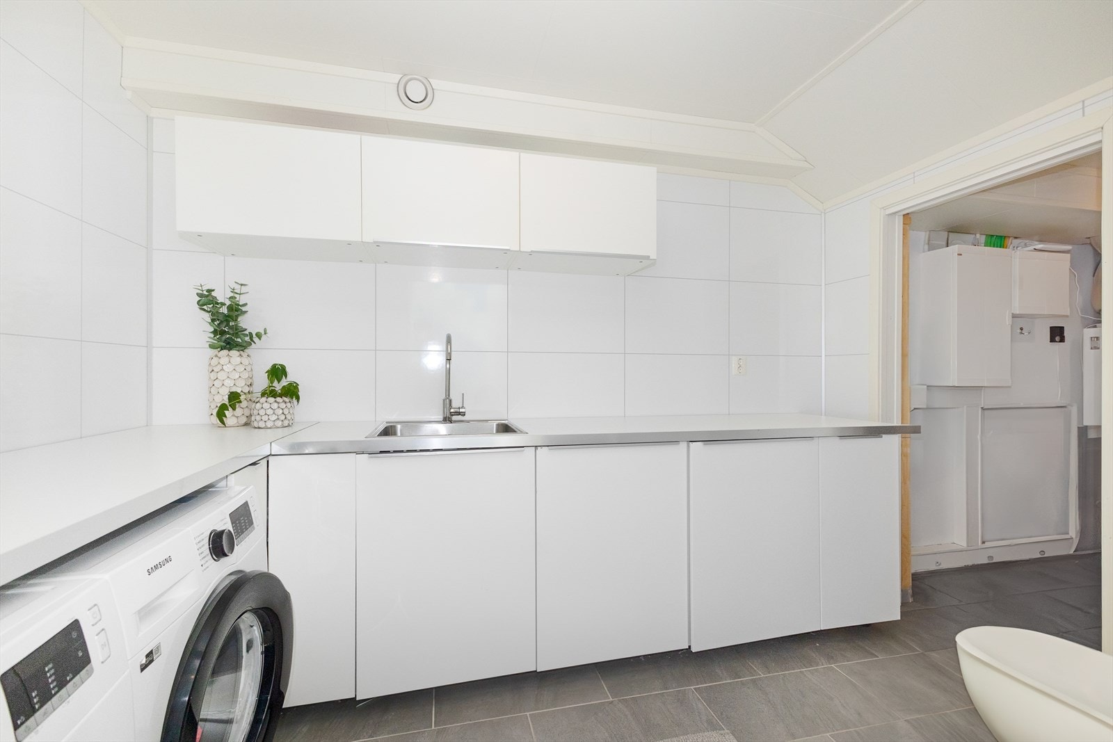 Separat vaskerom med wc. Herfra har man tilgang til ett teknisk rom, samt garderoberom som sammenføyer garasjen og hall i 1.etg sammen. Galleribilde