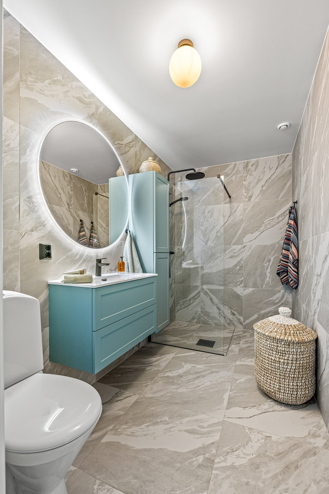 Badet er innredet med dusjhjørne med glassvegg, servant i innredningen, speil med lys, toalett og høyskap. Galleribilde