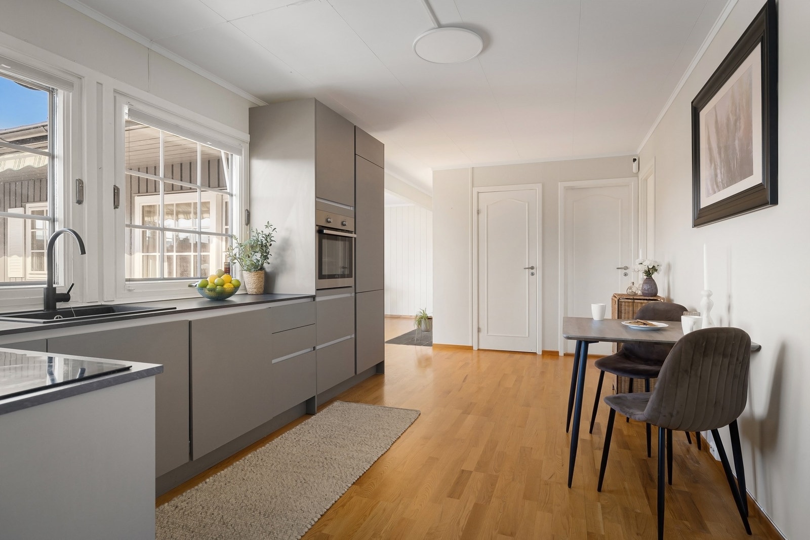 Integrerte hvitevarer som stekeovn, kjøleskap med frysedel, oppvaskmaskin og koketopp med ventilator over Galleribilde