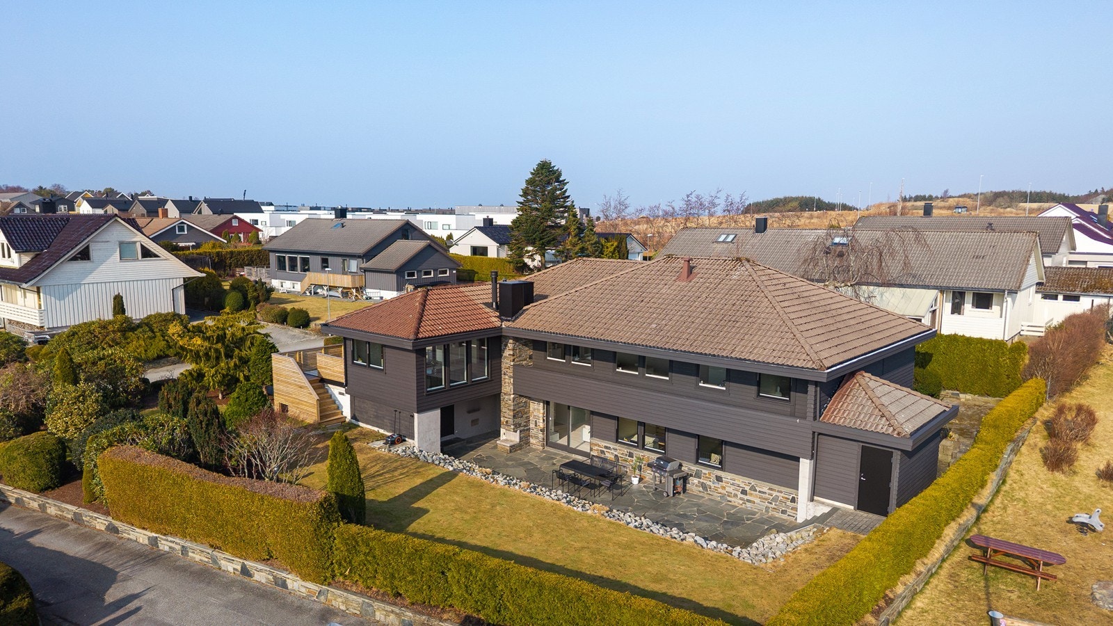 Pent opparbeidet uteområde med beplantning, hage, skiferterrasse og terrasse over garasje. Galleribilde