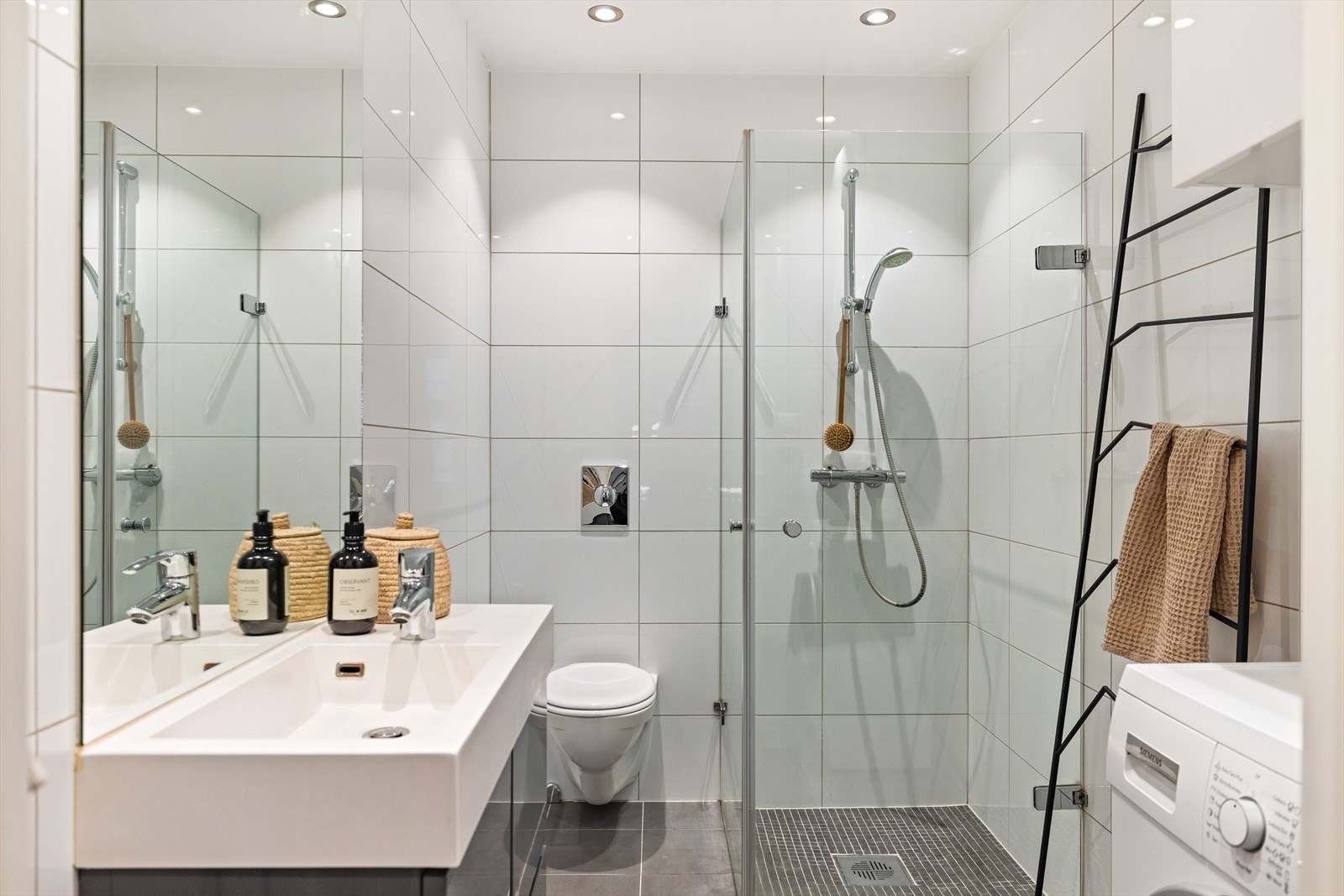 Badet er innredet med servantskap, vegghengt toalett og hjørnedusj med innfellbare glassdører. Galleribilde