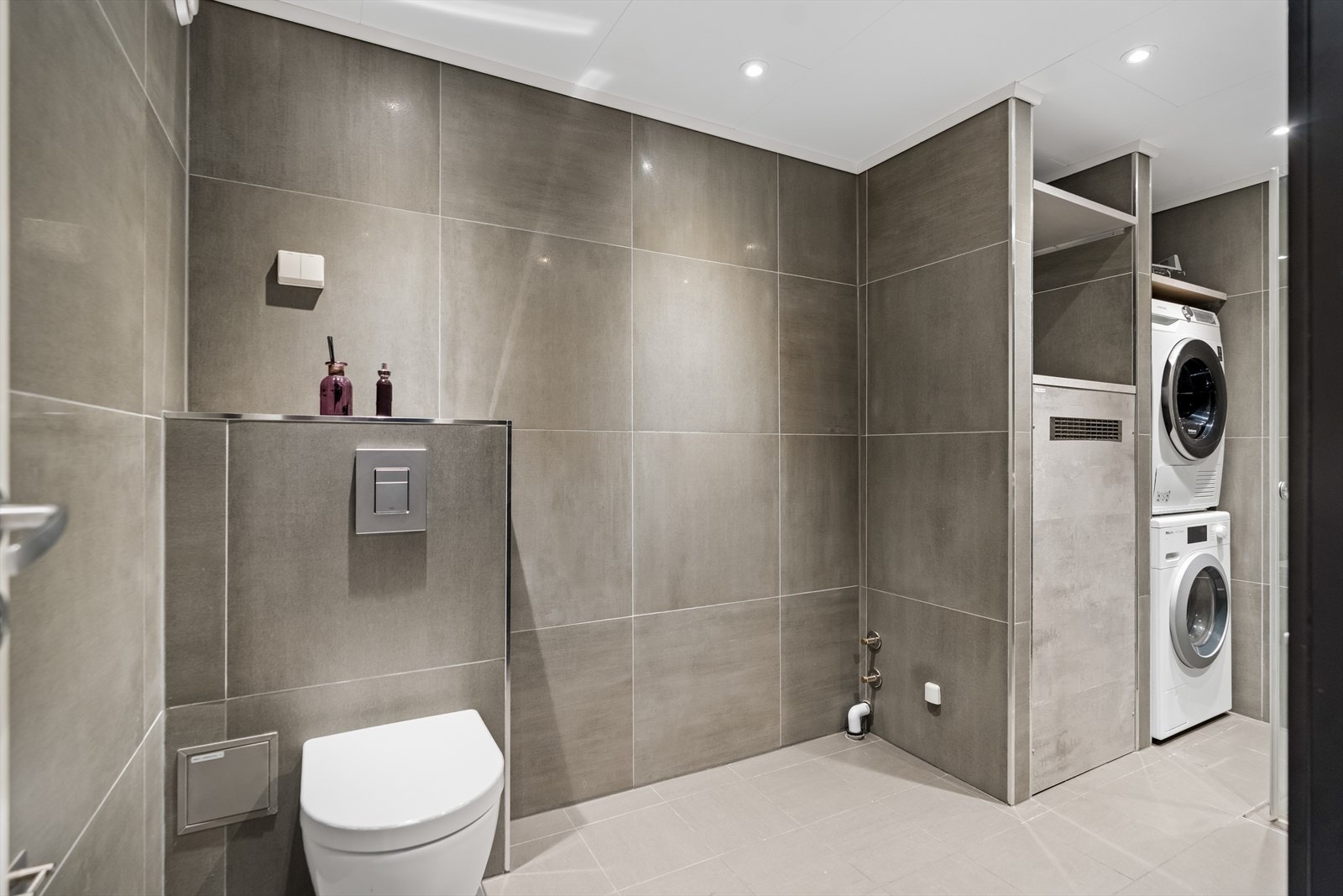 Videre er det satt inn servant, veggfestet klosett, dusj på gulv, opplegg for badekar og opplegg for vaskemaskin. Badet har mekanisk avtrekk. Galleribilde