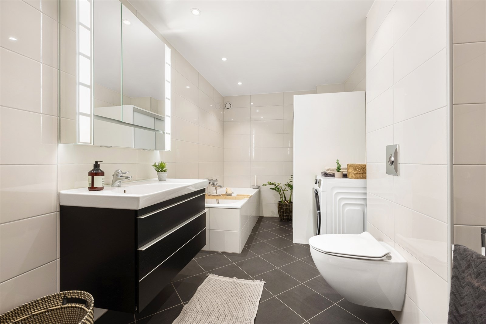 Moderne baderomsinnredning med servant, speilskap med lys og vegghengt toalett. Galleribilde