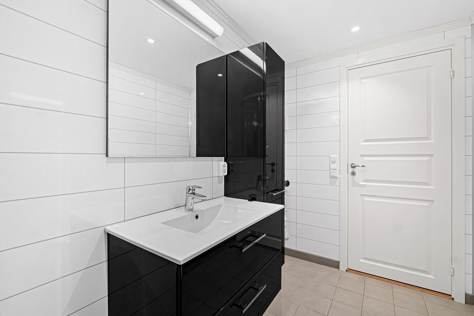 Her er det veggmontert toalett, dusjkabinett, baderomsinnredning i sort utførelse og opplegg for vaskemaskin Galleribilde