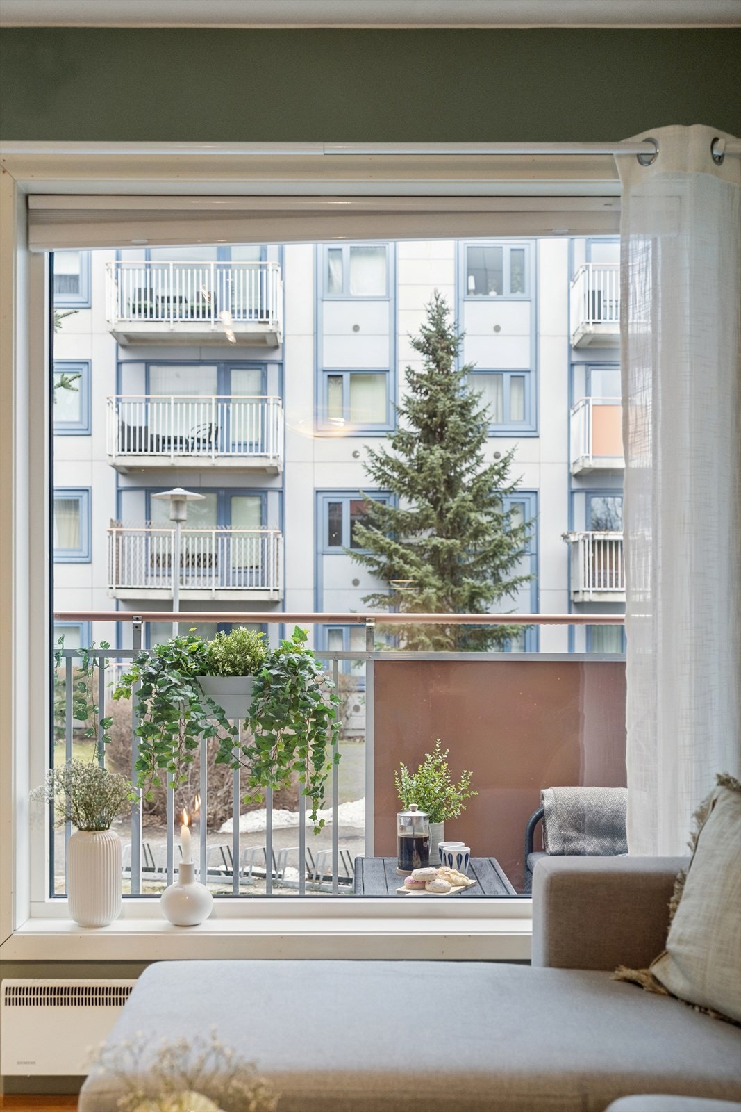 Stue med store vindusflater som gir rikelig dagslys og fin utsikt mot grøntområde og bakgård. Galleribilde