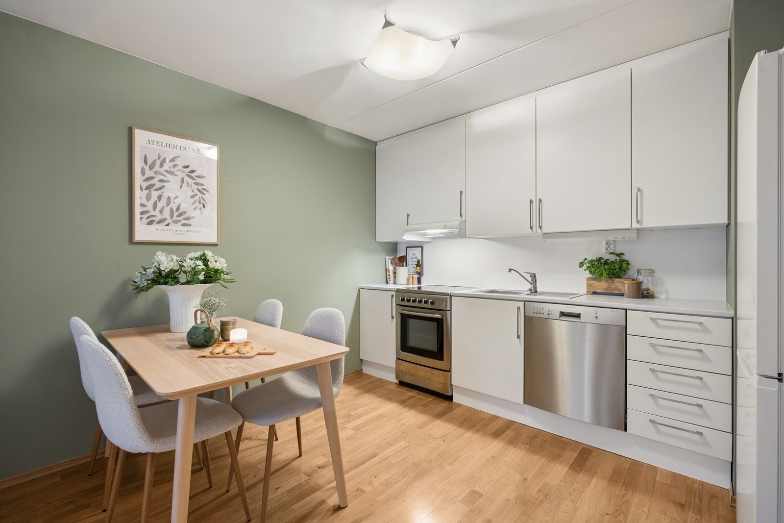 Her får du en praktisk kjøkkenløsning med integrert ventilator tilkoblet kanal, og en moderne, helhetlig stil som matcher den varme parketten og de lyse fargetonene. Galleribilde